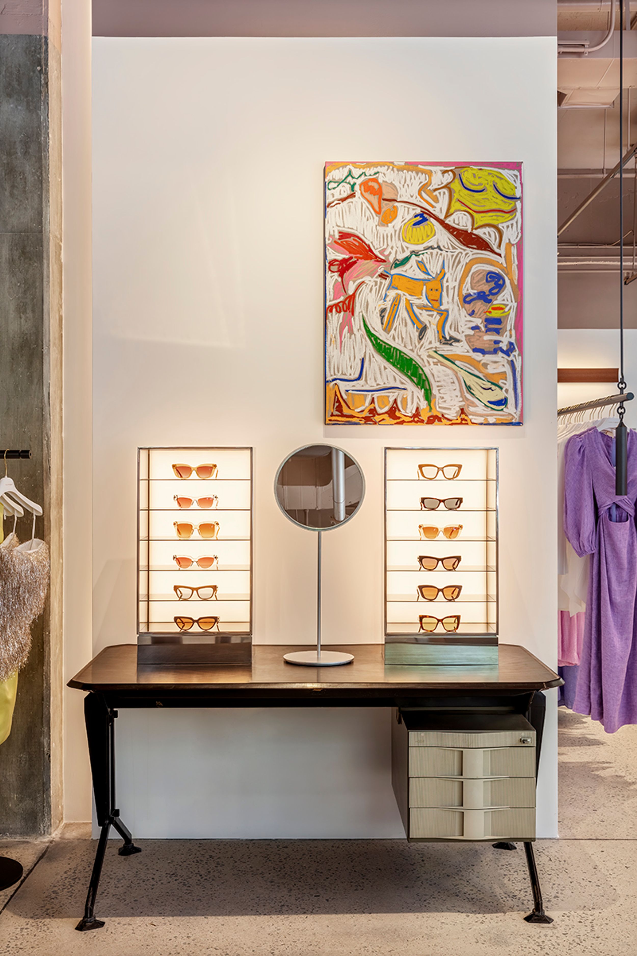 Table with two display units of sunglasses and a round mirror placed on top