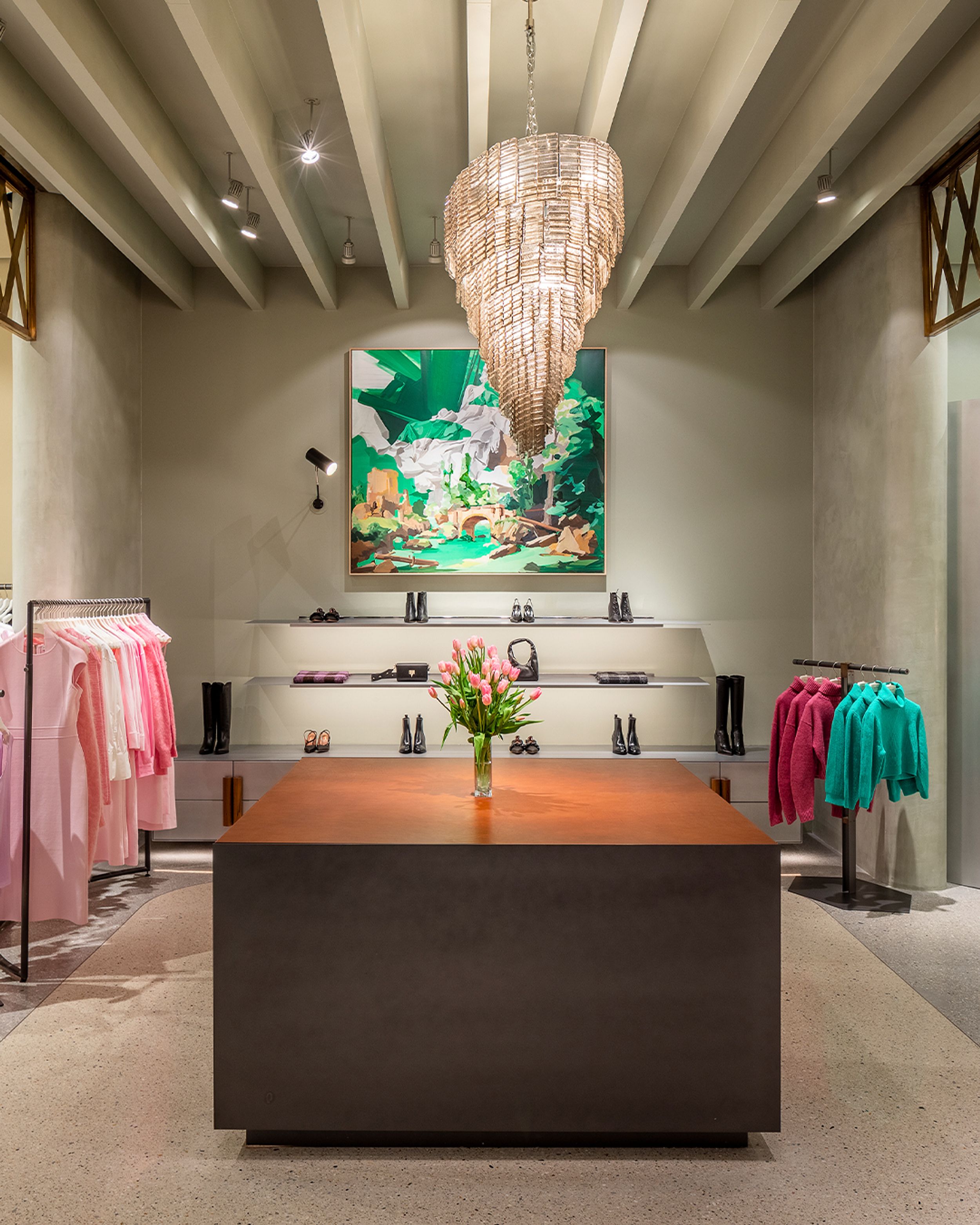 Interior of woman's fashion boutique with a large wooden counter counter, chandelier and colourful abstract painting