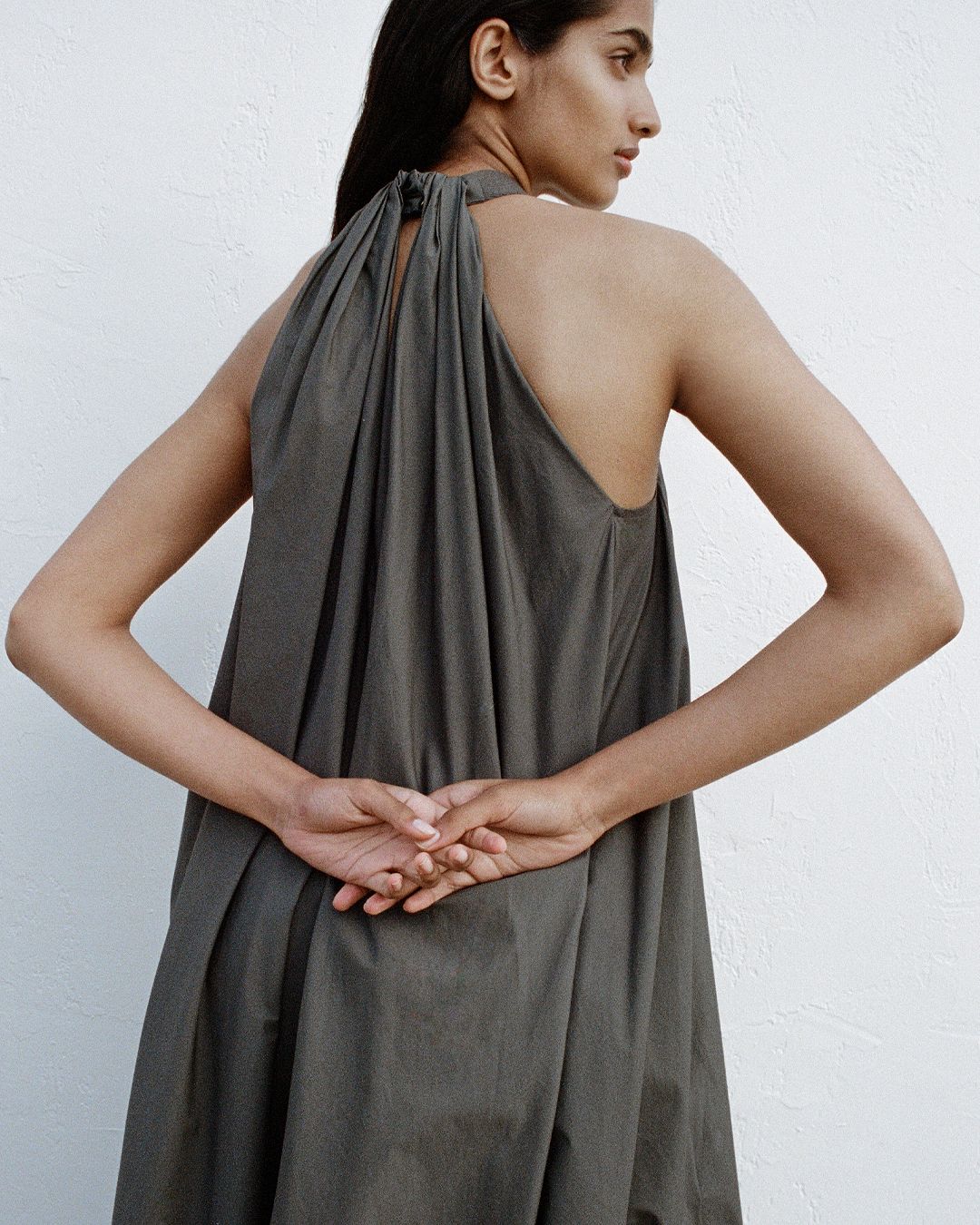 Girl facing away from the camera looking over her shoulder holding hands behind her back.