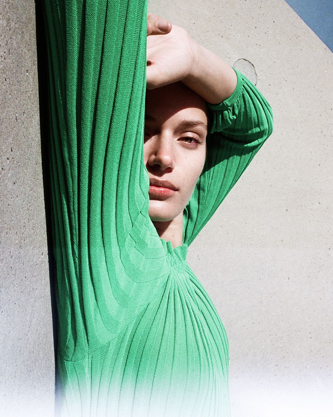 Head shot of brunette girl with shadow coming across her face, one eye squinting from the sun.