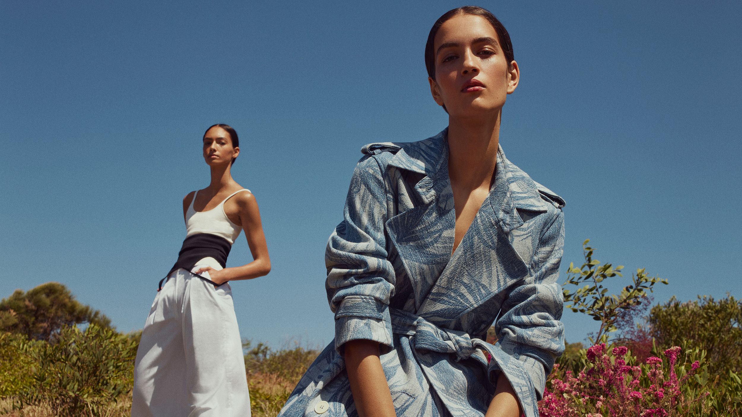 Two models gazing at the camera wearing a denim palm-print jacket and white singlet with trousers