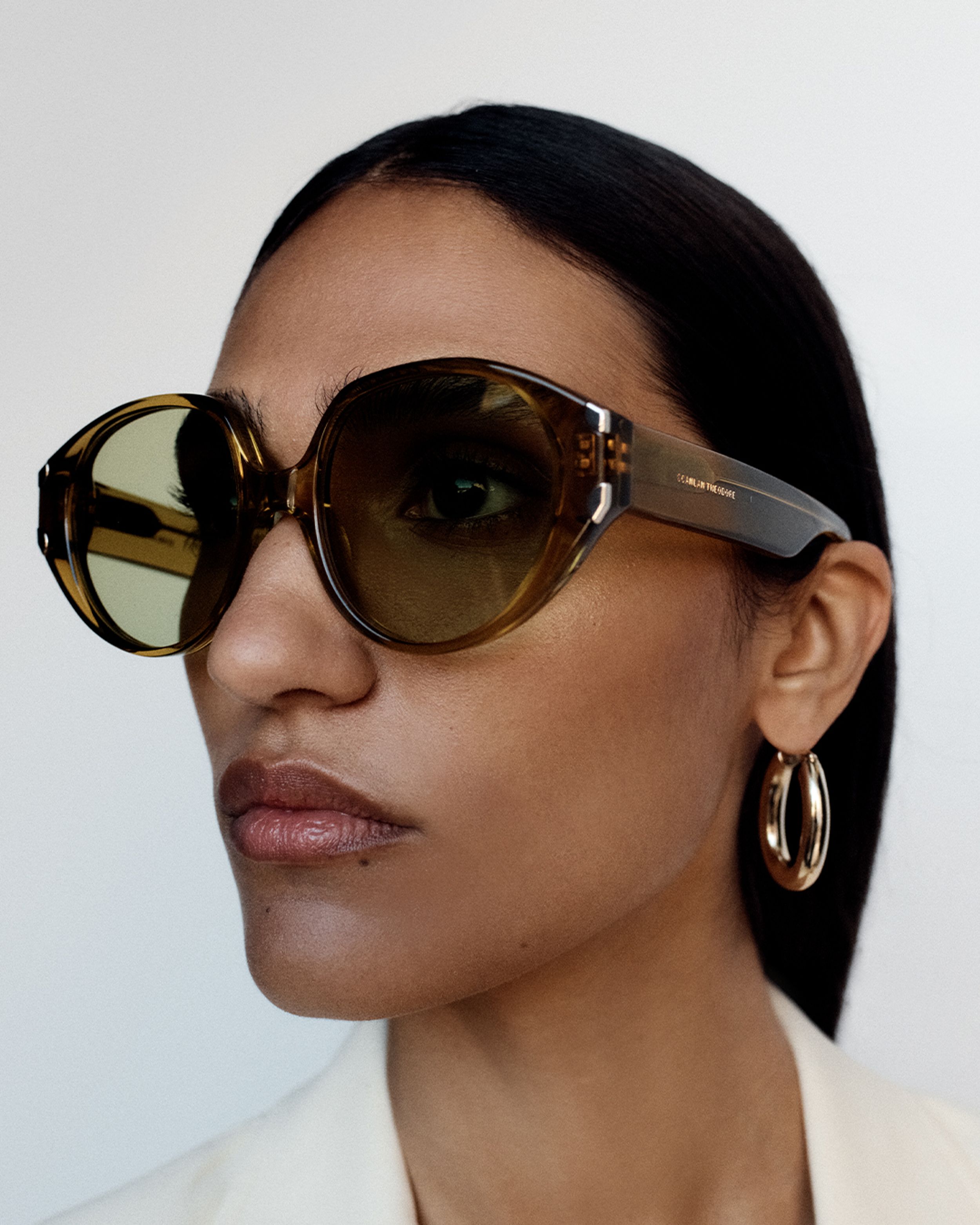 Close up of model looking to the side wearing khaki round sunglasses