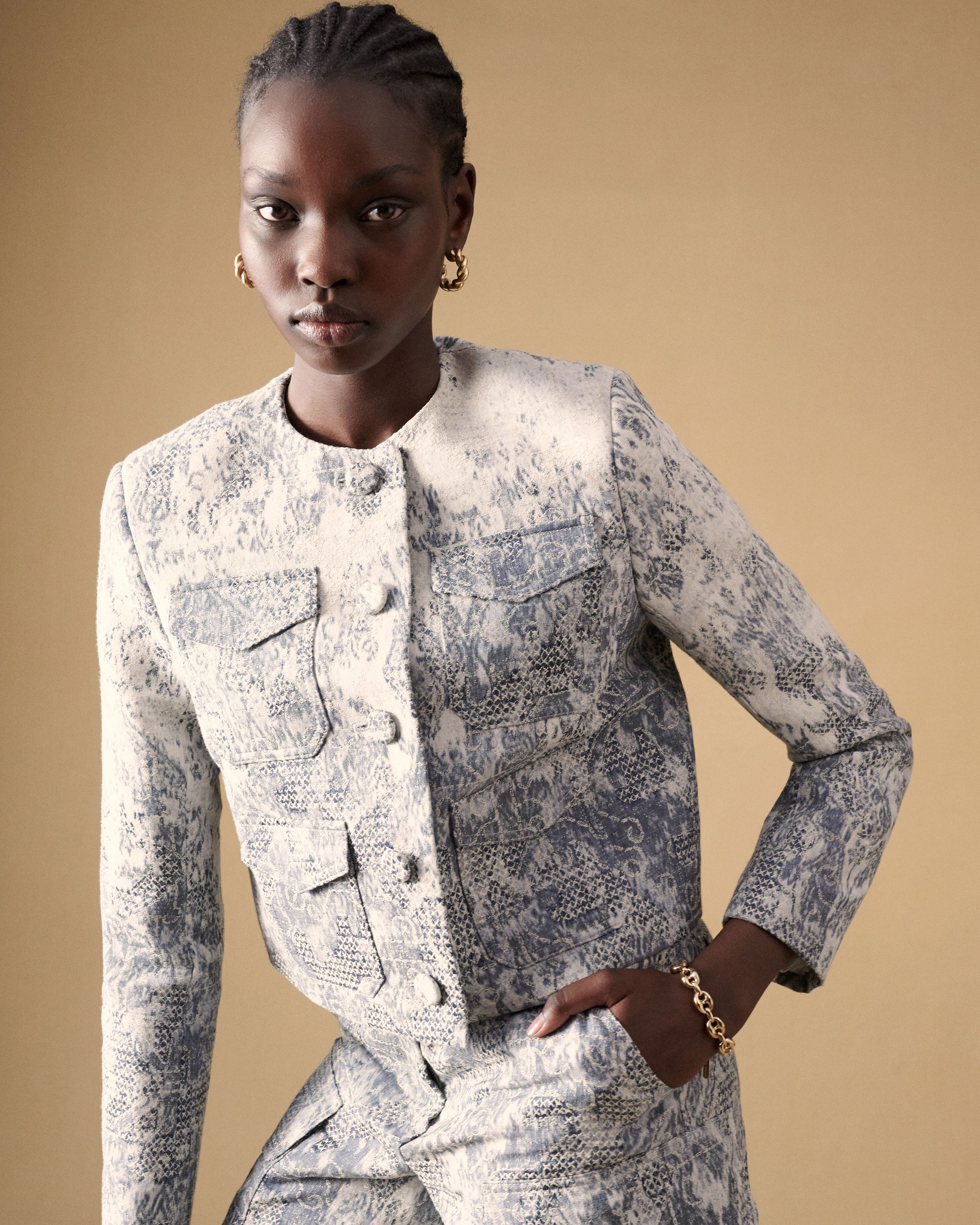 Model posing with hand in pocket wearing a matching blue and white jacket and shorts