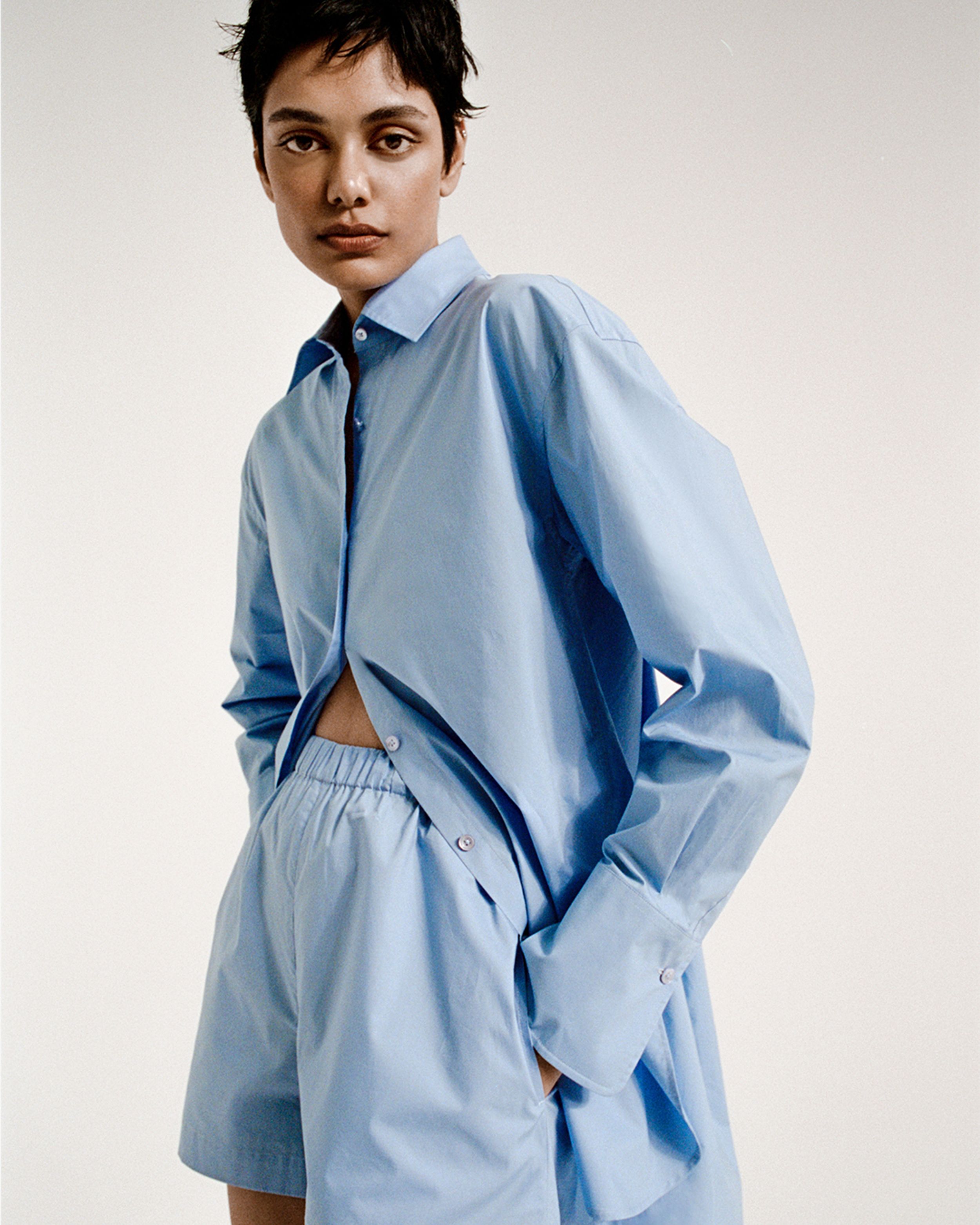 Zinnia Kumar posing with hands in pockets wearing a blue cotton shirt and matching shorts