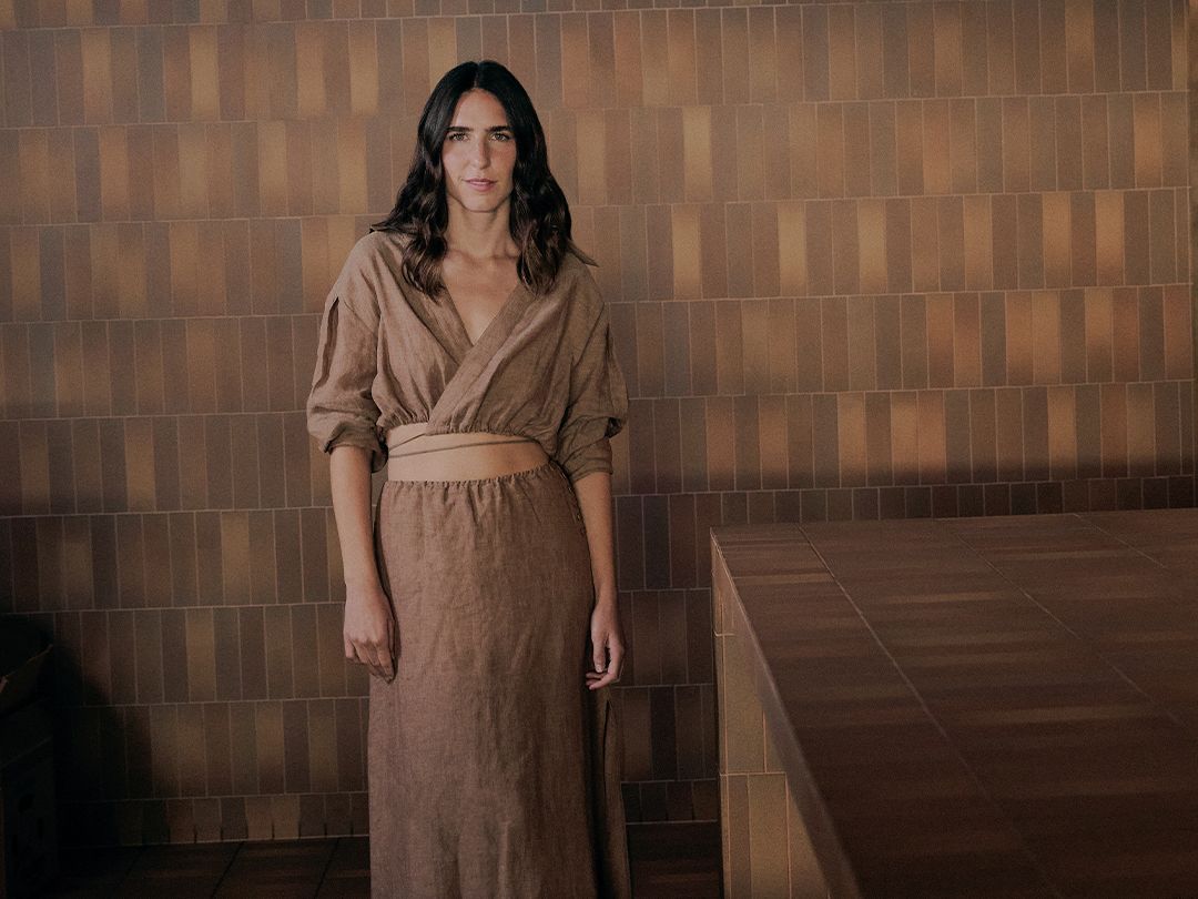 Restauranteur Bianca Marchi wearing a brown linen shirt and skirt standing in front of a brown tiled wall