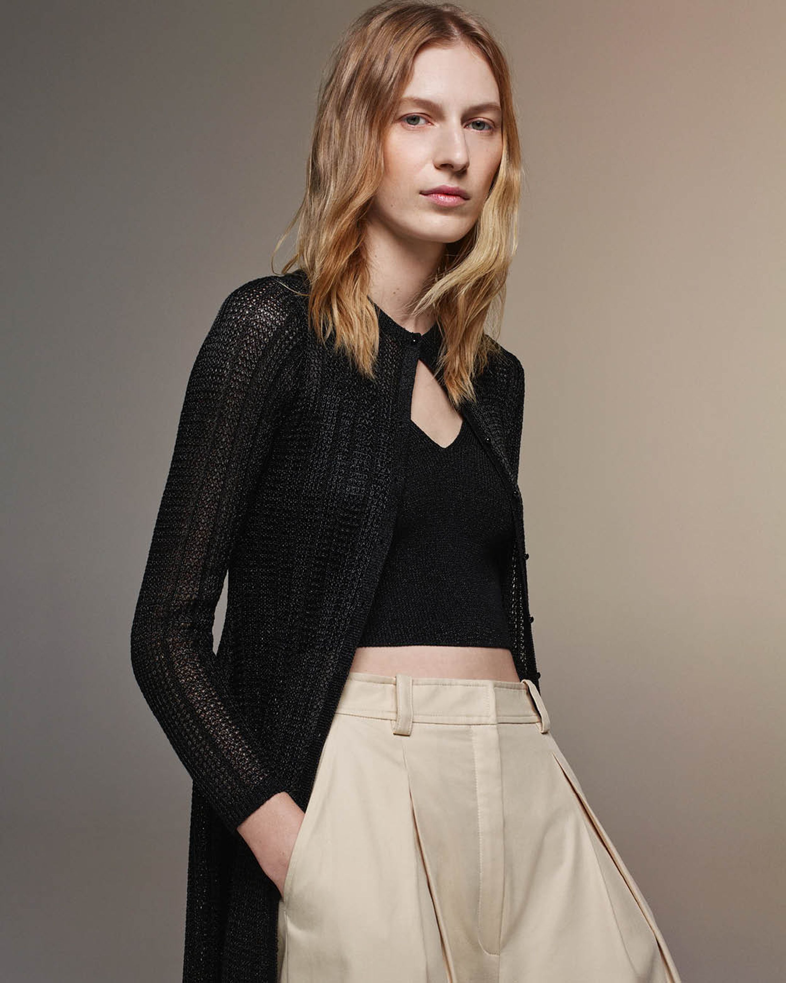 Julia Nobis wearing a matching black singlet and cardigan with beige trousers