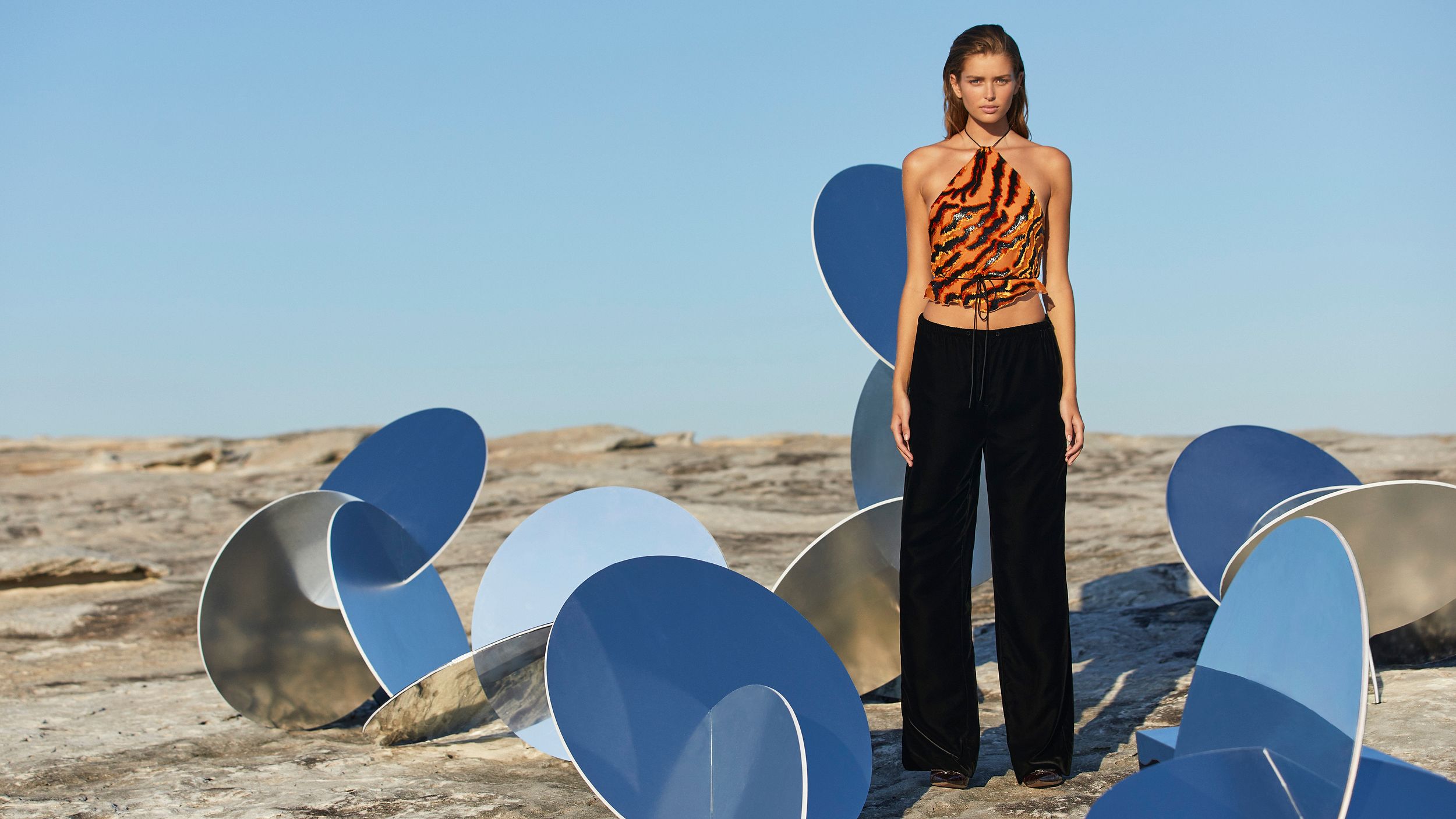 Models posing outdoors amongst mirrored sculptures and a white inflatable structure for the Winter 2024 collection