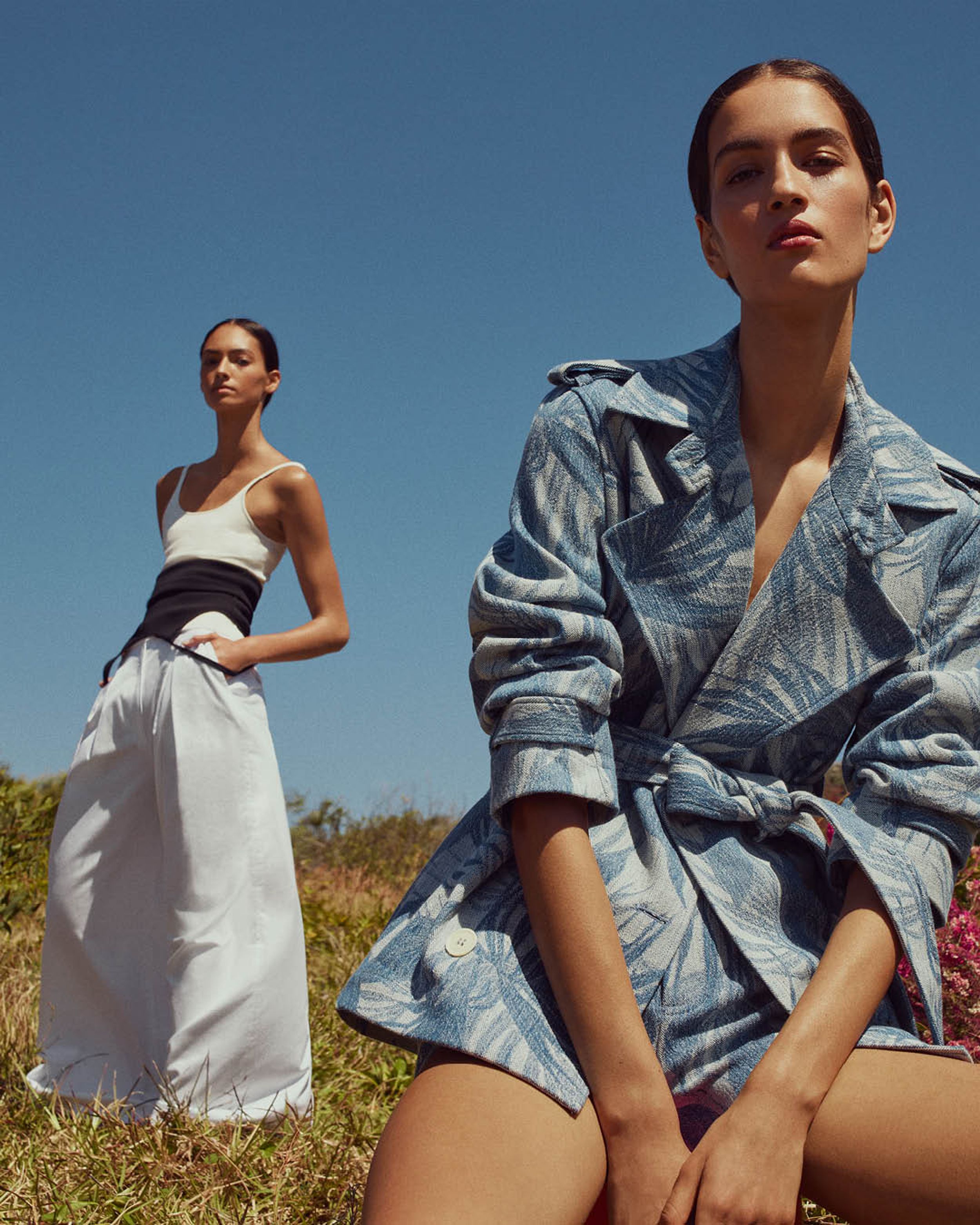 Two models gazing at the camera wearing a denim palm-print jacket and white singlet with trousers