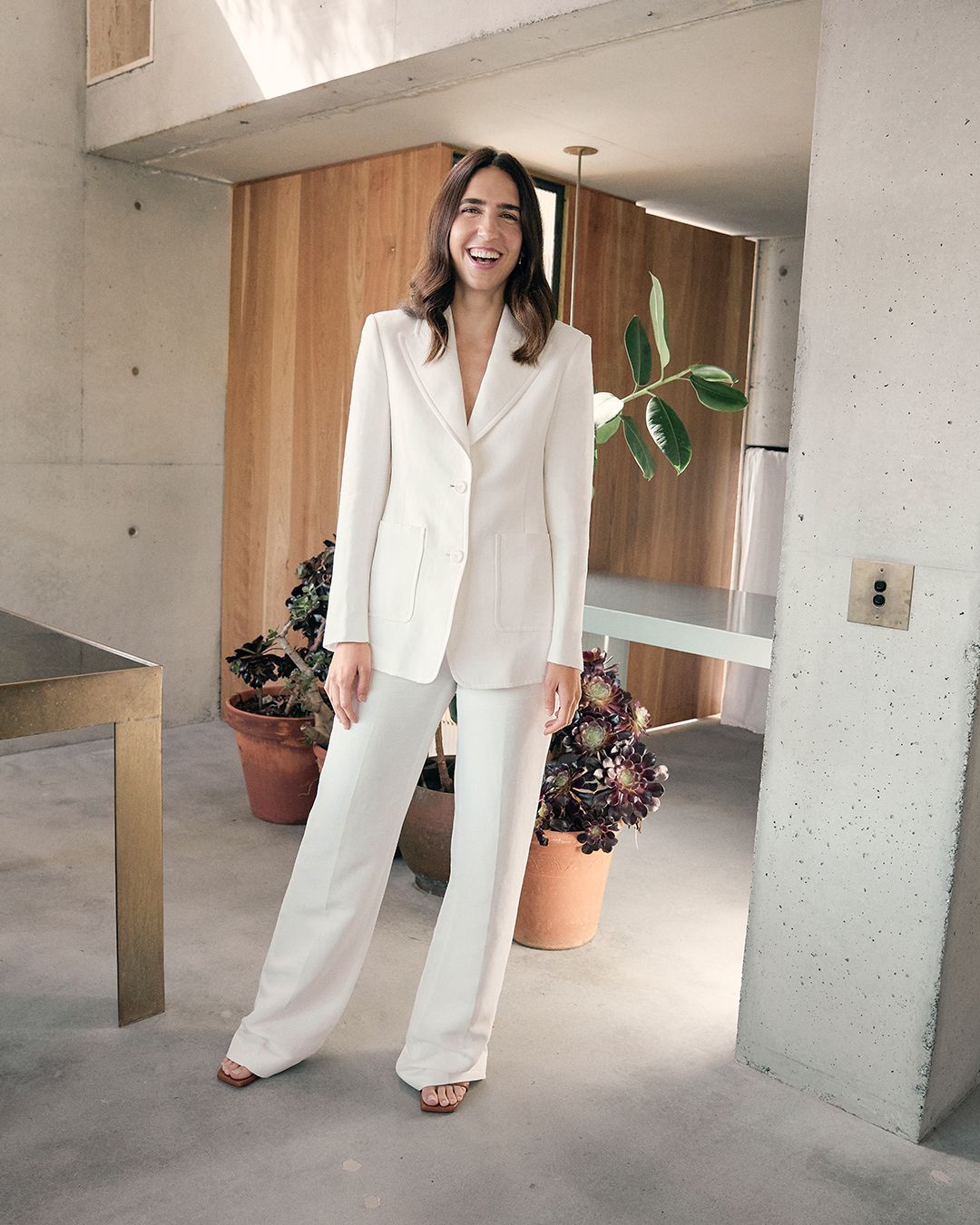 Bianca Marchi standing in a white pantsuit in an minimalistic entrance way