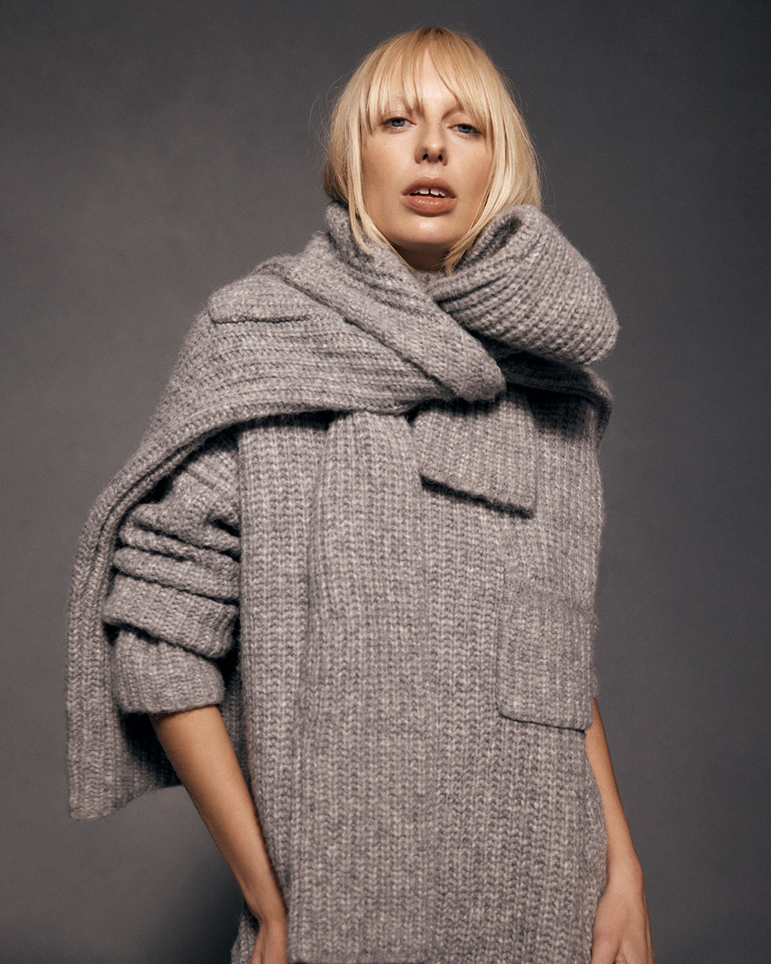 Blonde model wearing a grey melange knitted sweater
