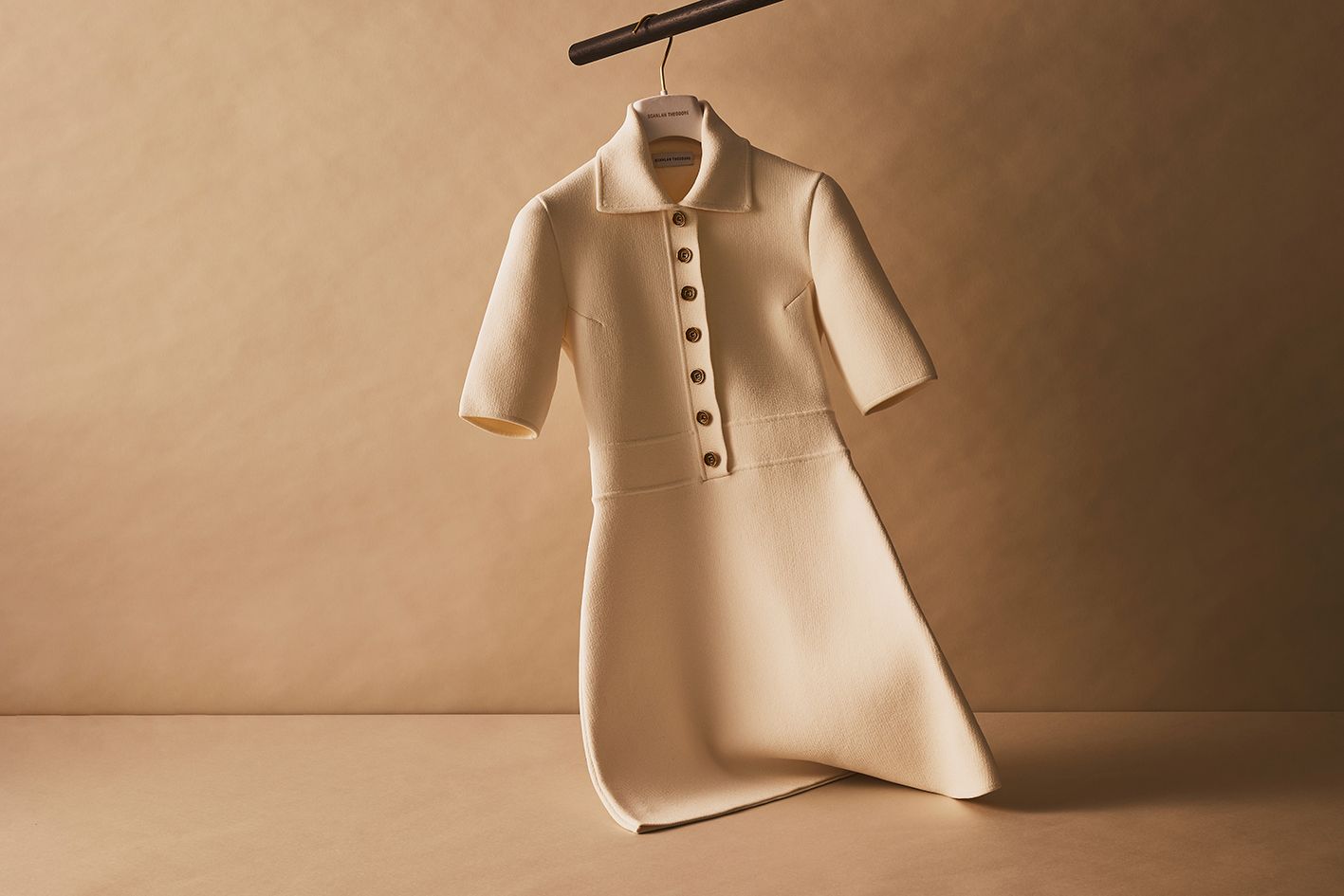 Scanlan Theodore cream crepe knit button dress with short sleeves hanging on a rail.