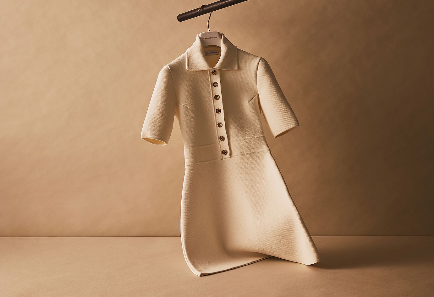 Scanlan Theodore cream crepe knit button dress with short sleeves hanging on a rail.