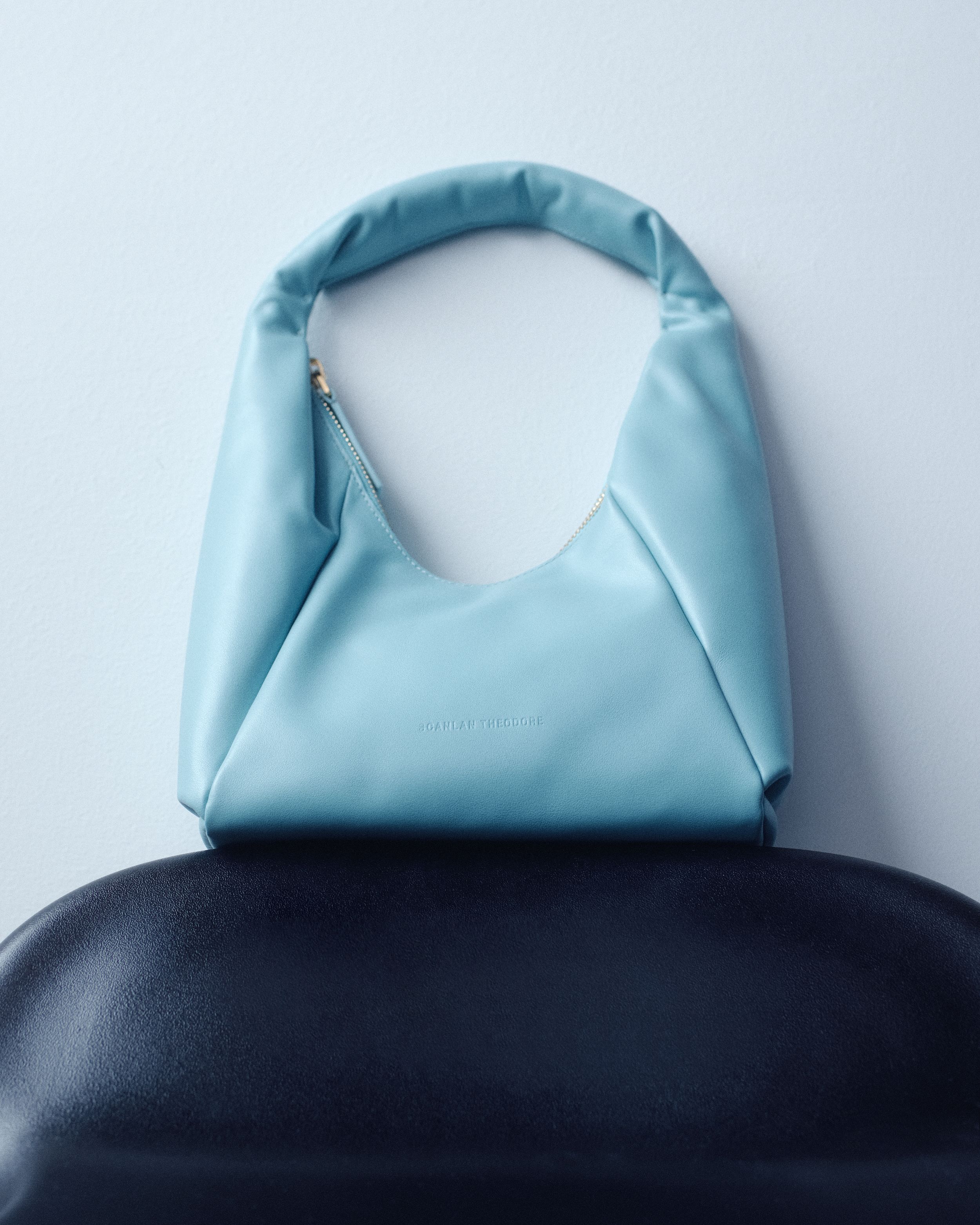 Light blue leather bag on black surface with white background