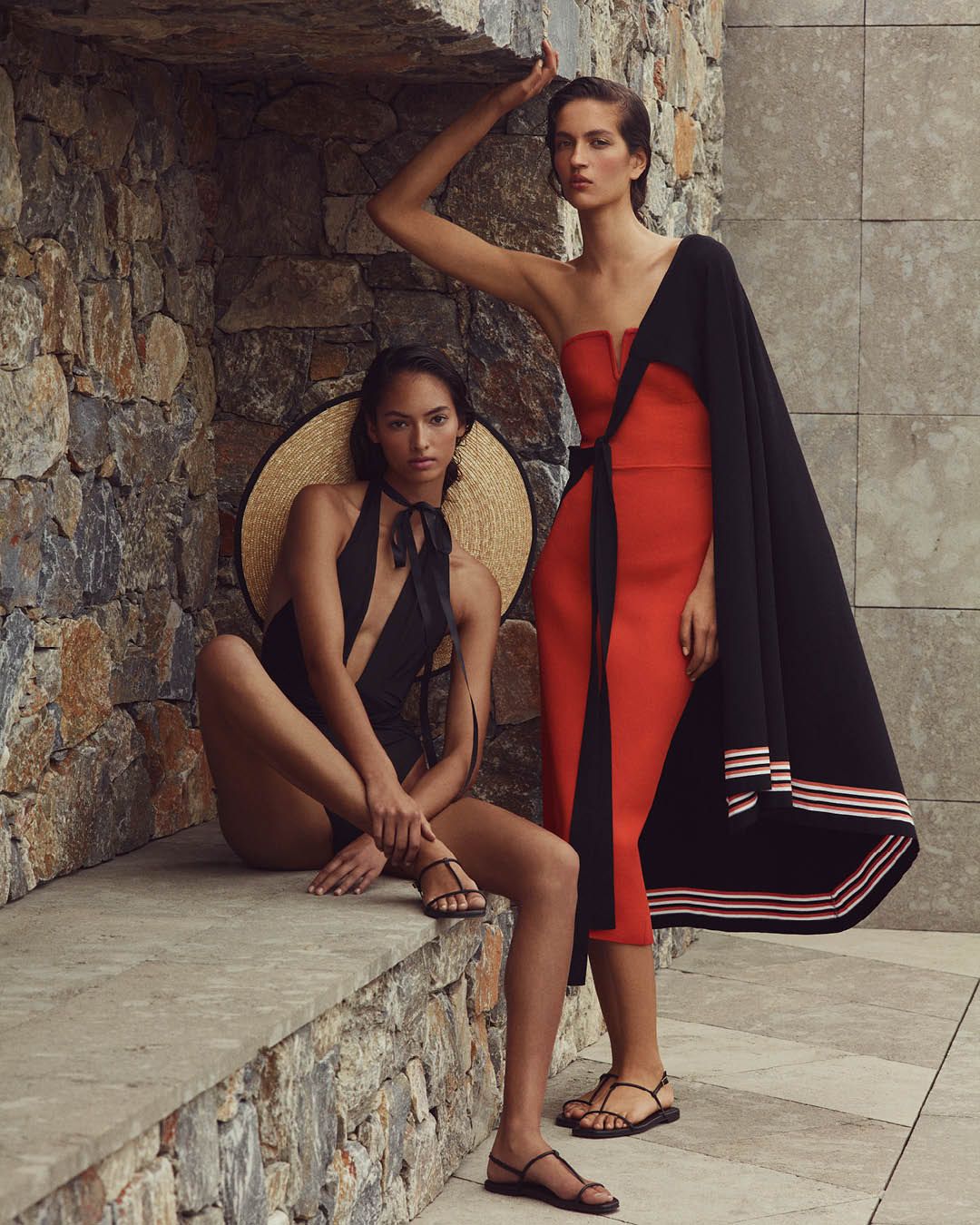 Two models posing - left model wearing a black one-piece swimsuit, right model wearing a red strapless dress