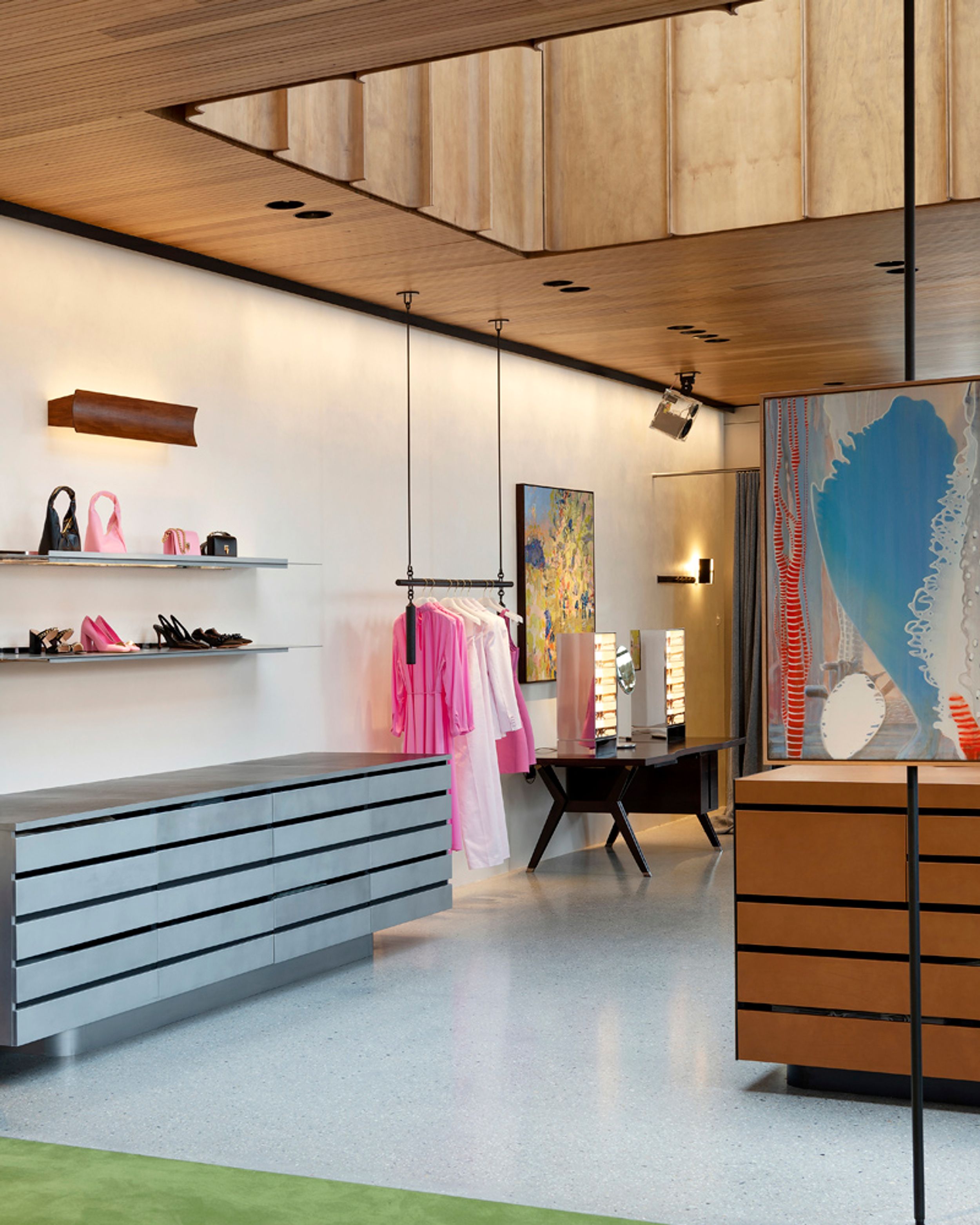 Store interior with hanging rack of pink clothing, sunglasses station, and shelf of pink and black accessories