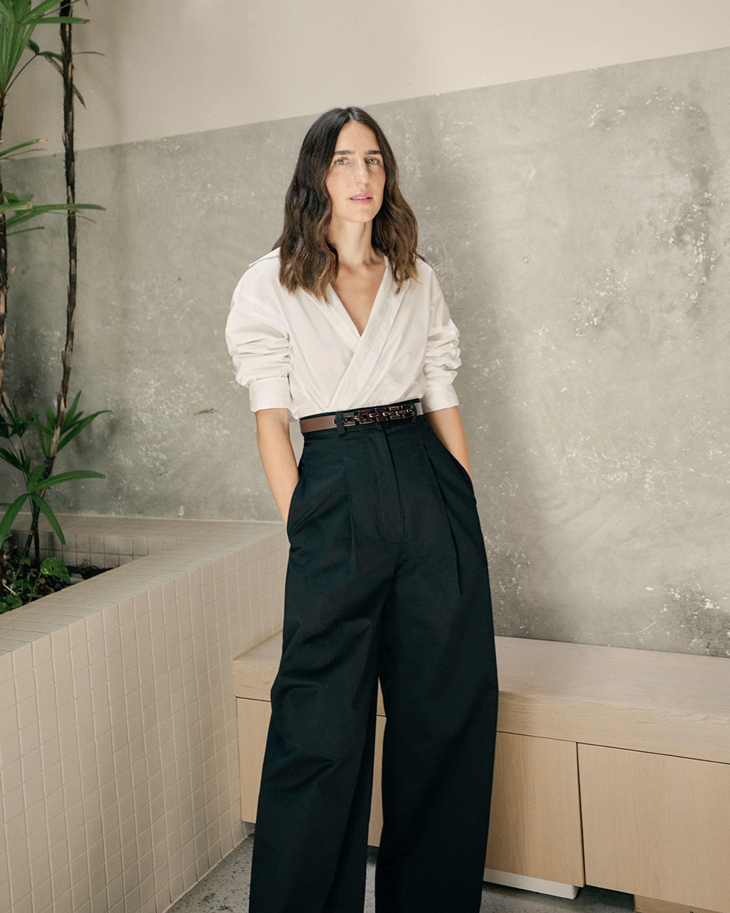 Bianca Marchi posing front on in a white shirt and black wide leg trousers with hands in pockets