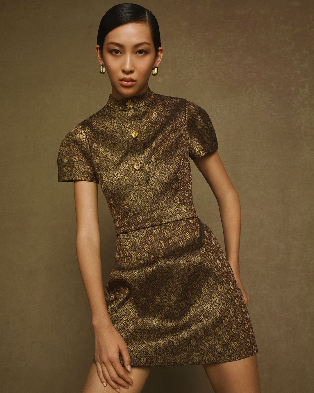 Model posing wearing Bronze French Brocade mini dress with short sleeves