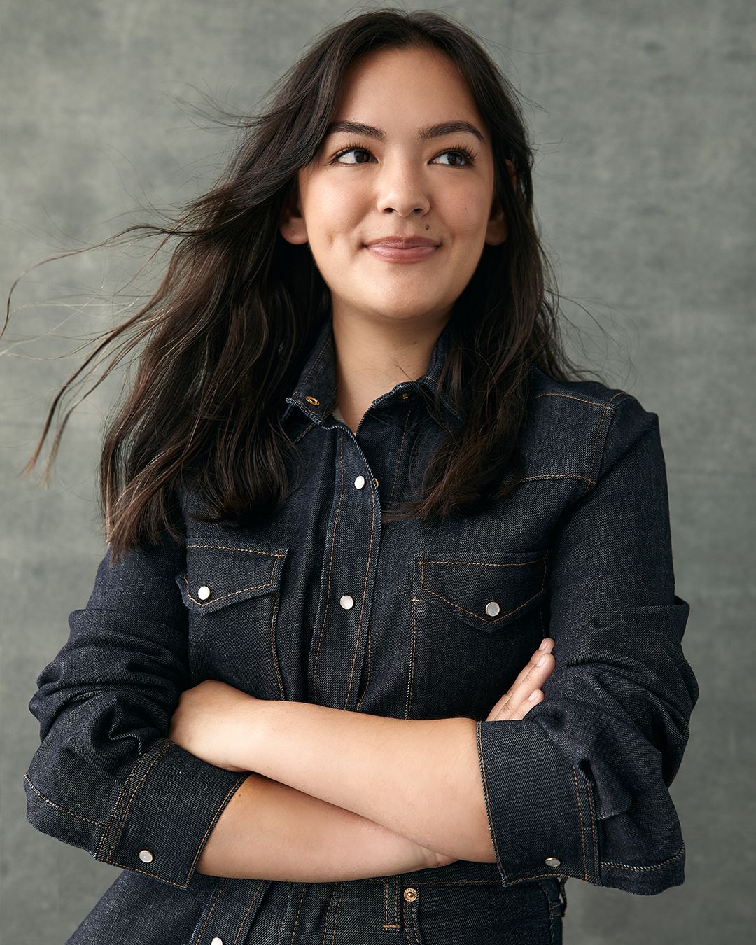 Vogue Codes winner and engineer Grace Brown with long brown hair posing with arms crossed in denim shirt