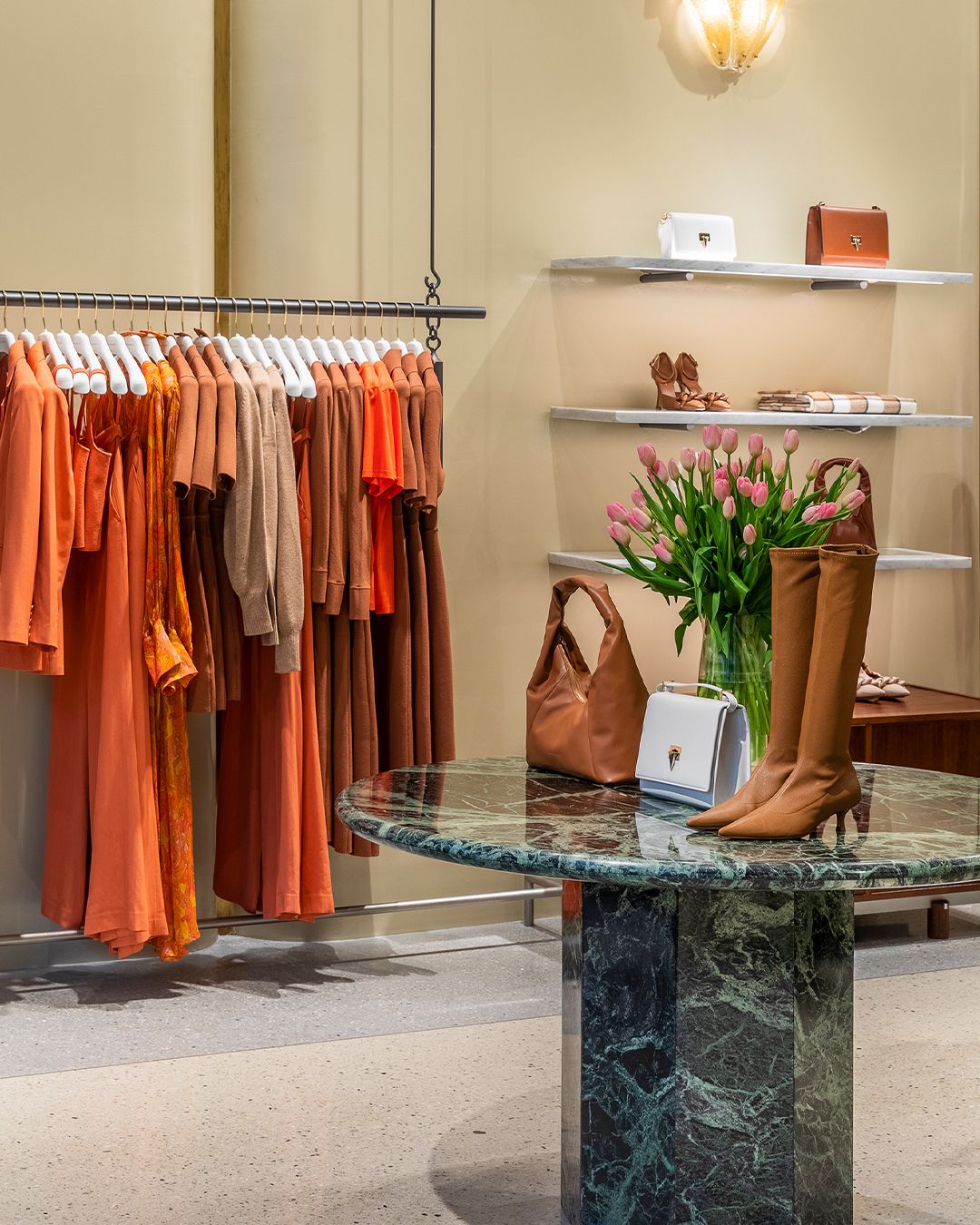 Interior of a women's fashion boutique with orange clothing and tan-coloured accessories