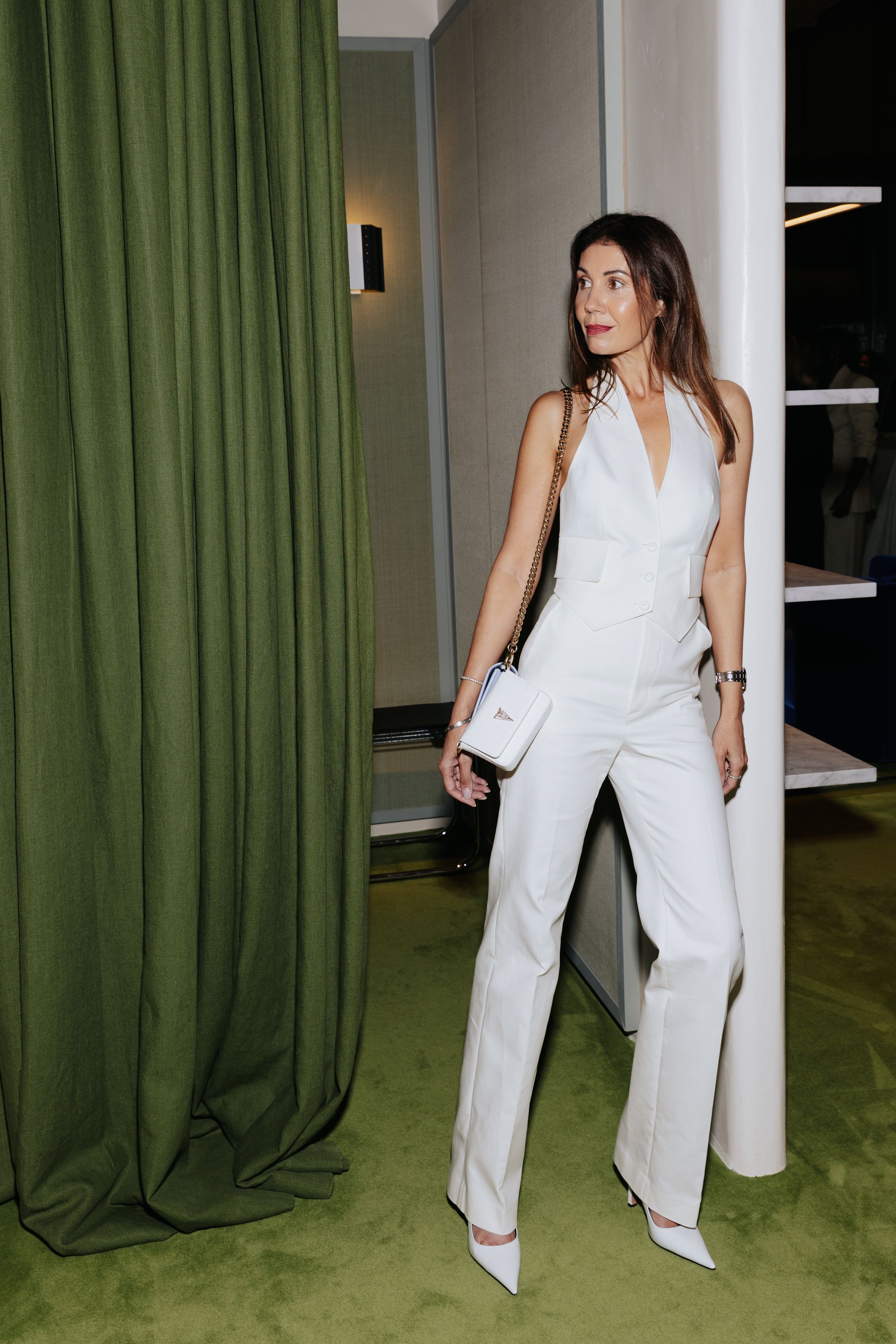Woman standing next to fitting room wearing white vest and trousers