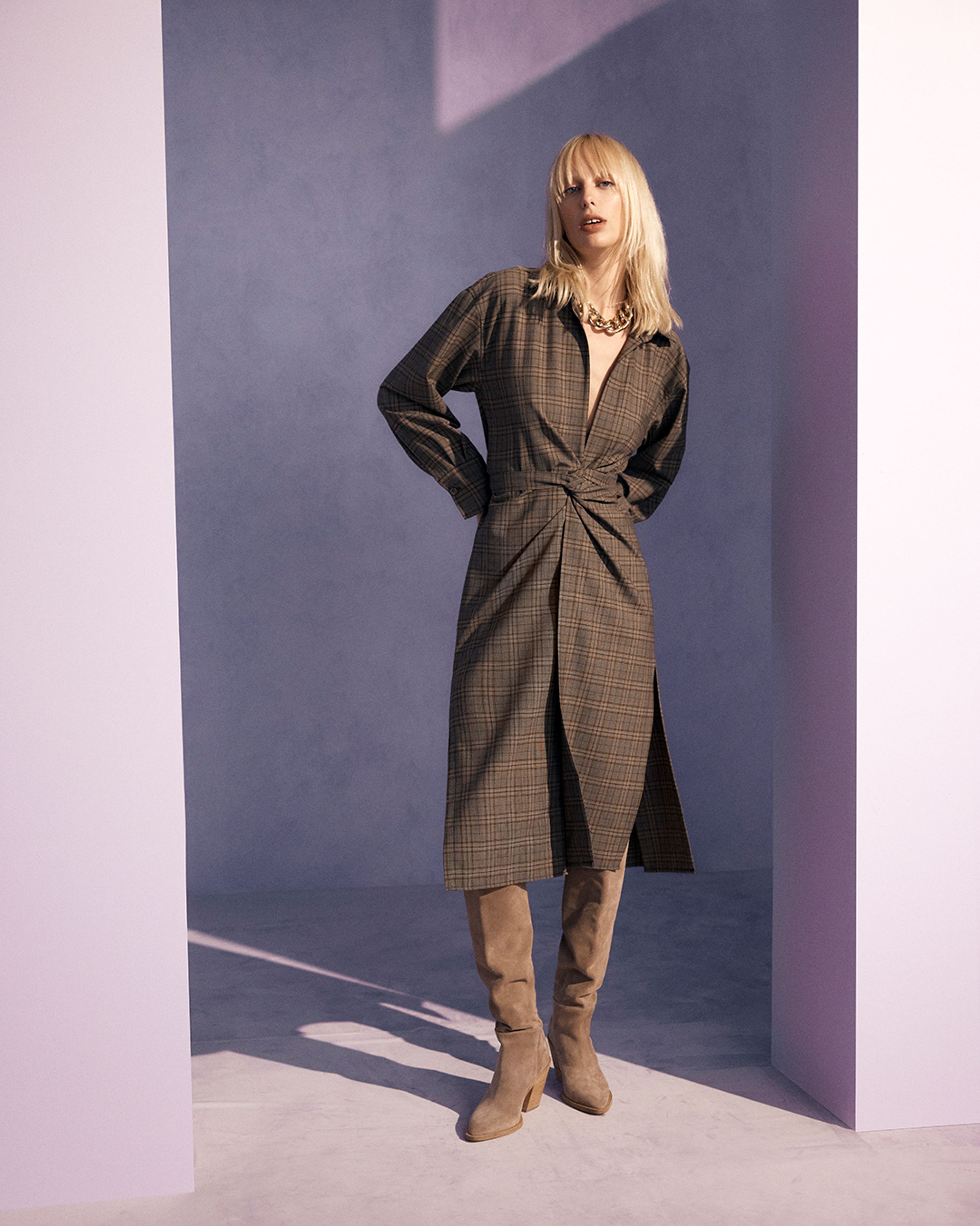 Blonde model standing in a brown shirt dress and brown suede boots