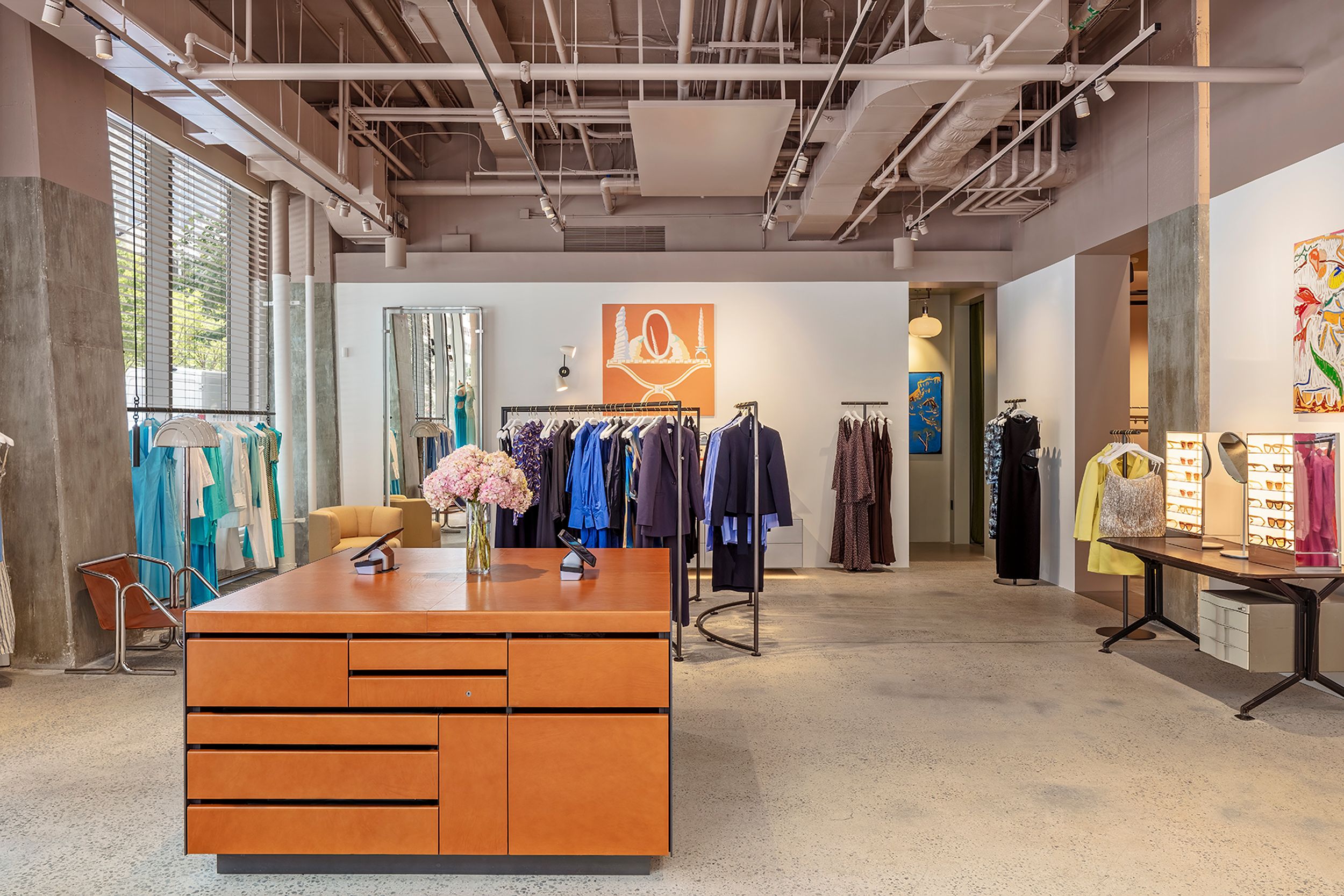 Interior of store with large wooden counter and blue clothing on racks