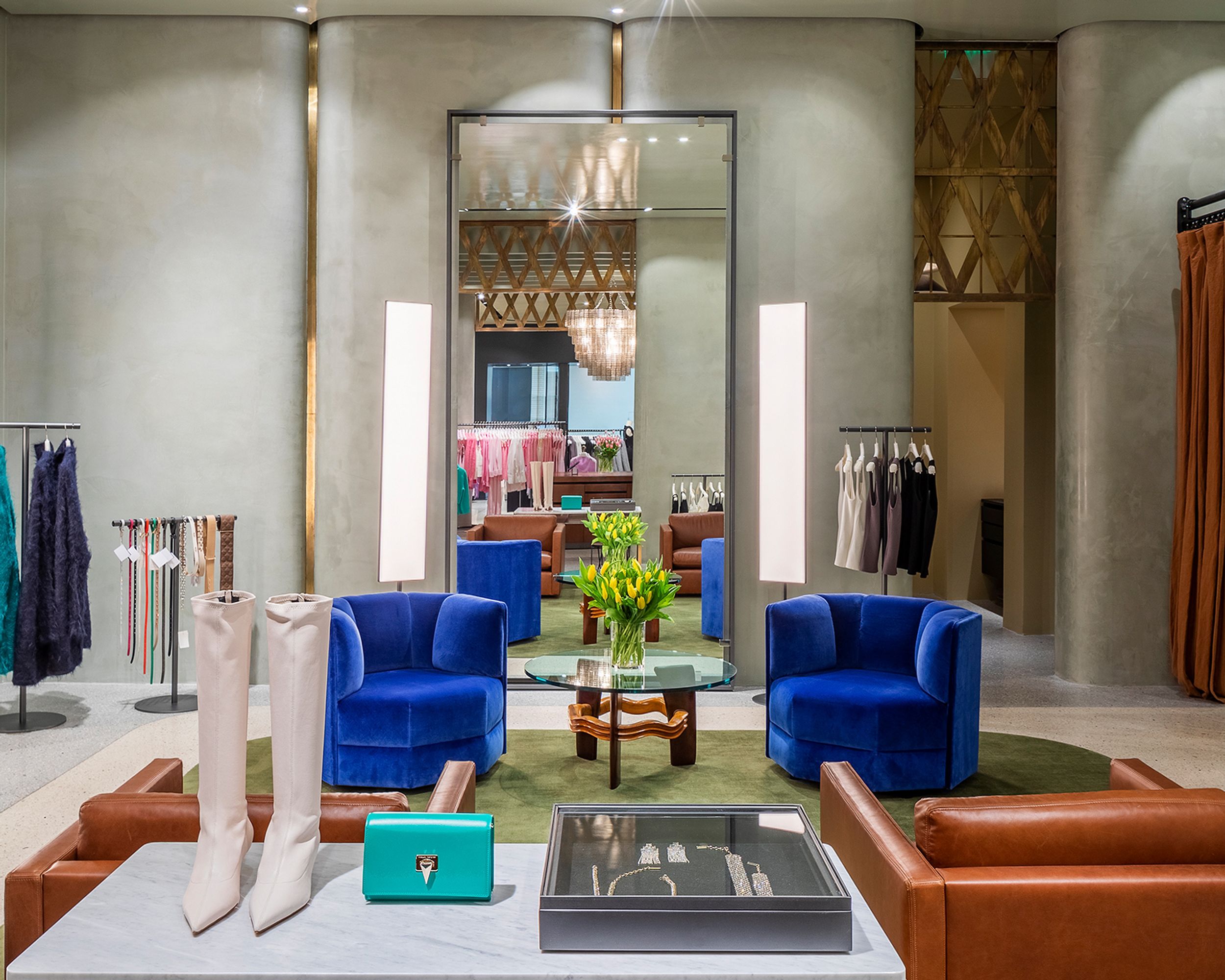 Interior of woman's fashion boutique with accessories on display, large mirrors, and blue velvet seats