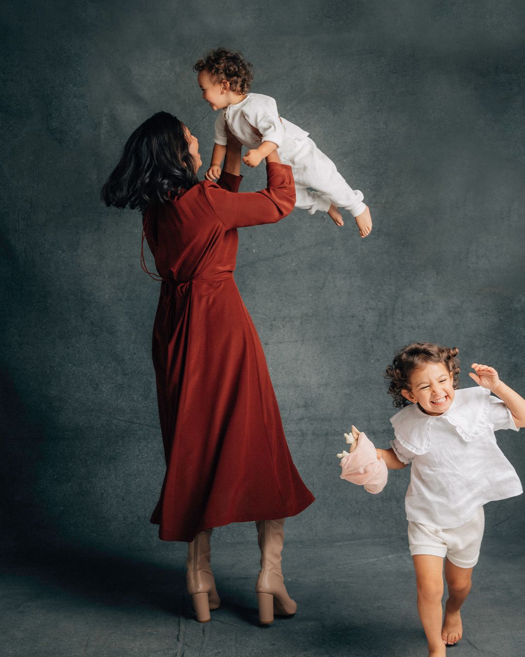 Shamini Rajarethnam wearing a rust silk midi dress candidly playing with her two children