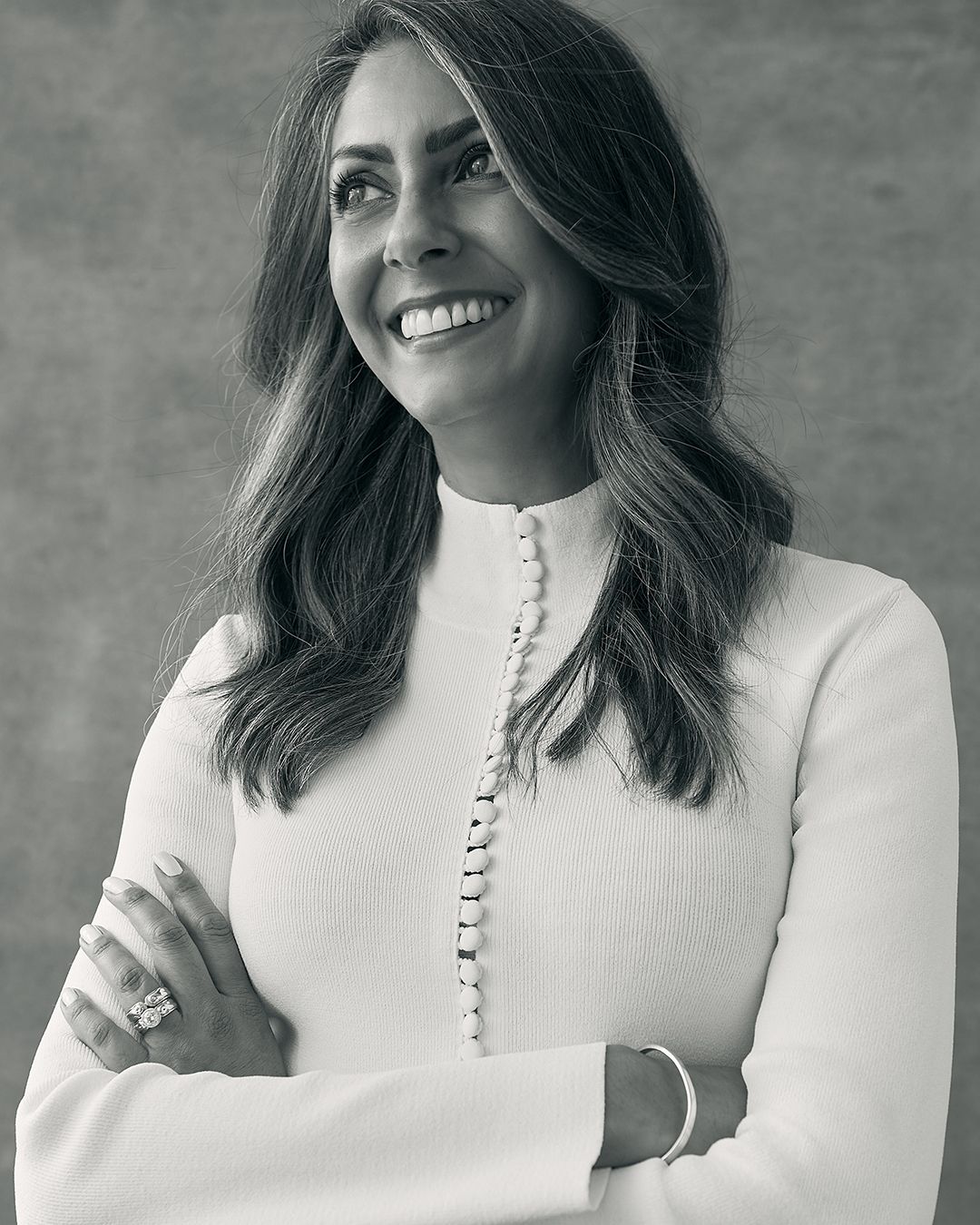 Executive leader Shirley Chowdhary in White Crepe Knit Button Polo Sweater with arms crossed