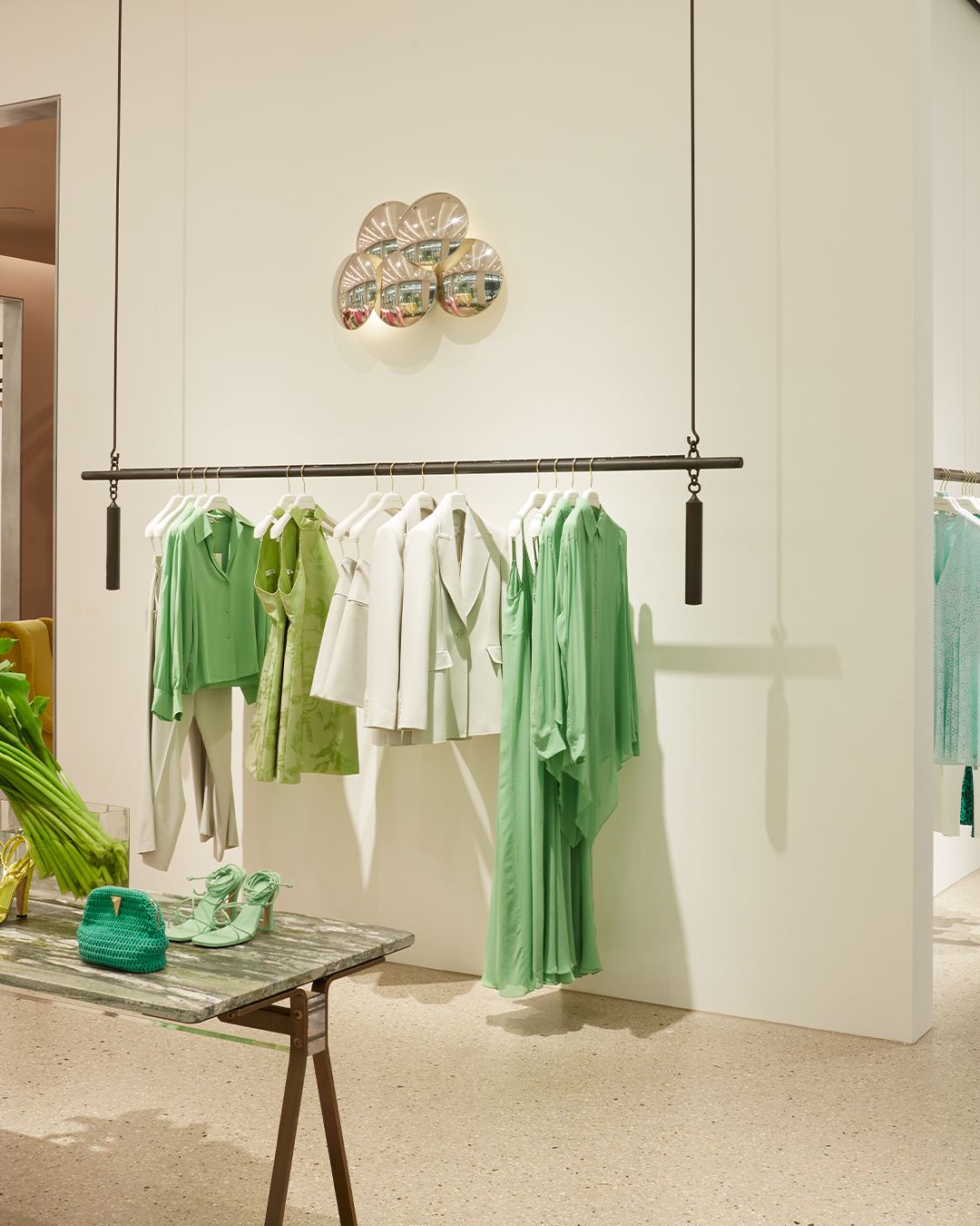 Interior of women's fashion boutique with clothing rack featuring green and white clothing