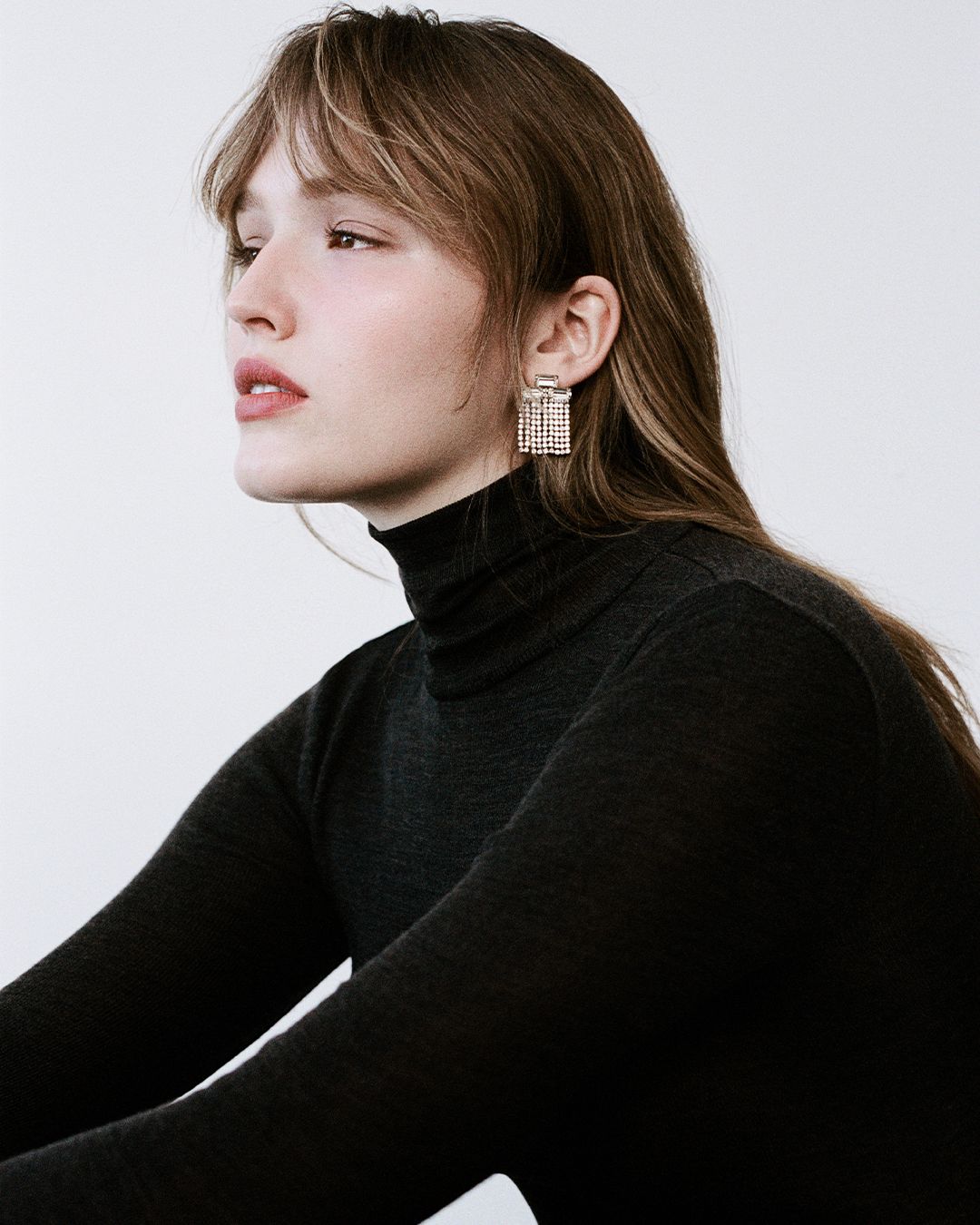 Maddison Brown posing wearing a Black Babywool Polo Top and diamante drop earrings