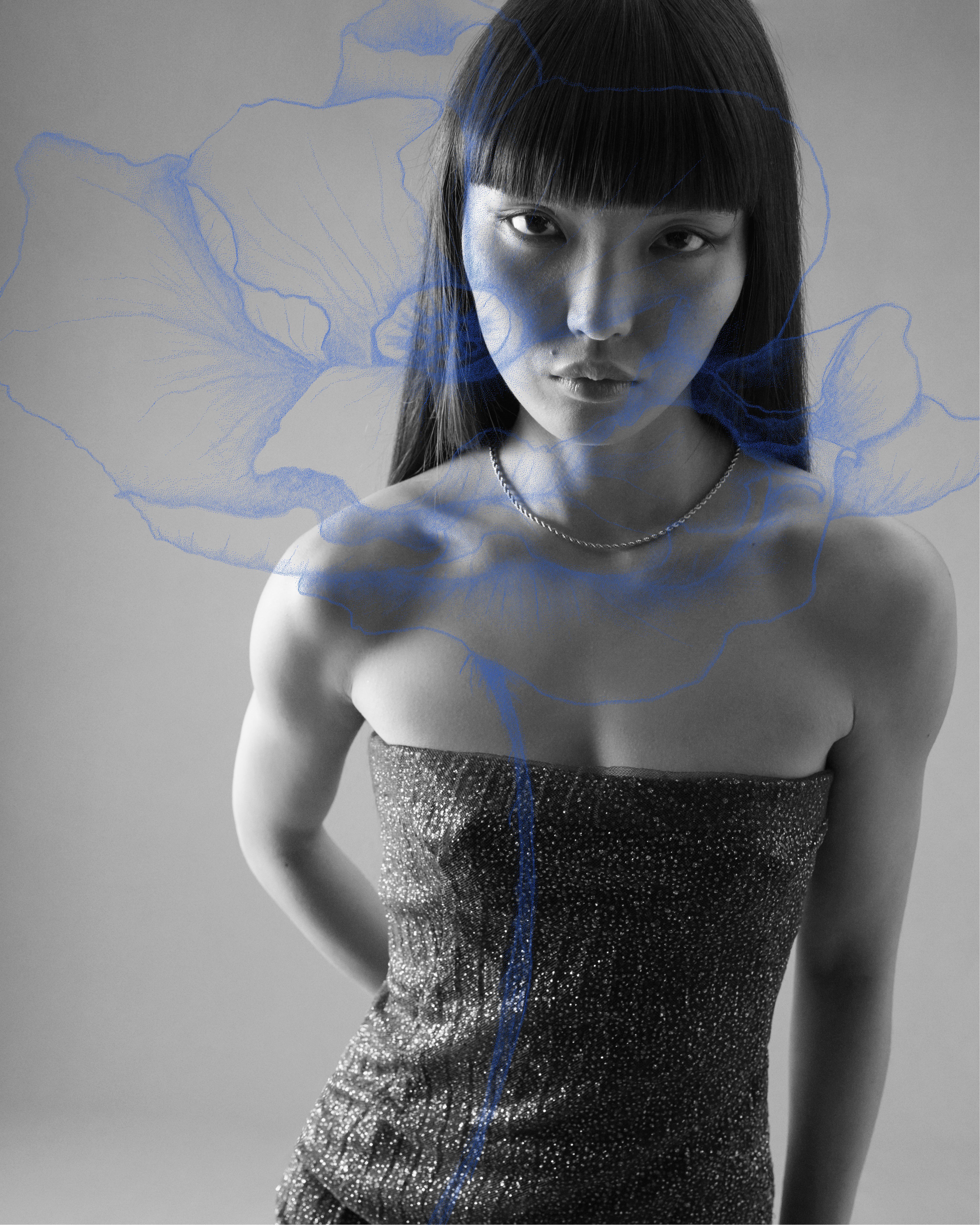 Black and white image of model gazing at camera in strapless dress with blue poppy illustration overlaid on top