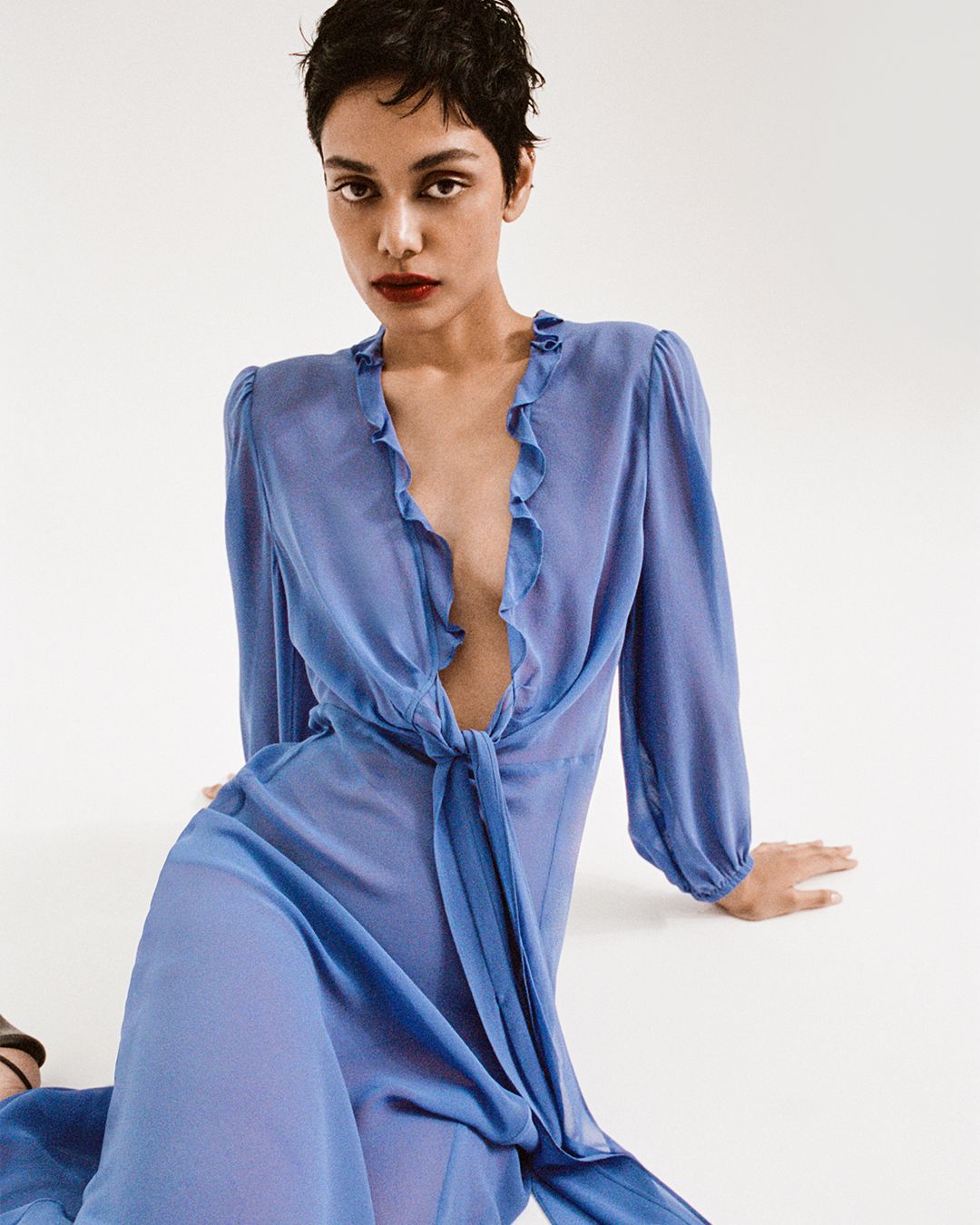 Zinnia Kumar sitting on the floor in a blue silk dress with ruffled collar
