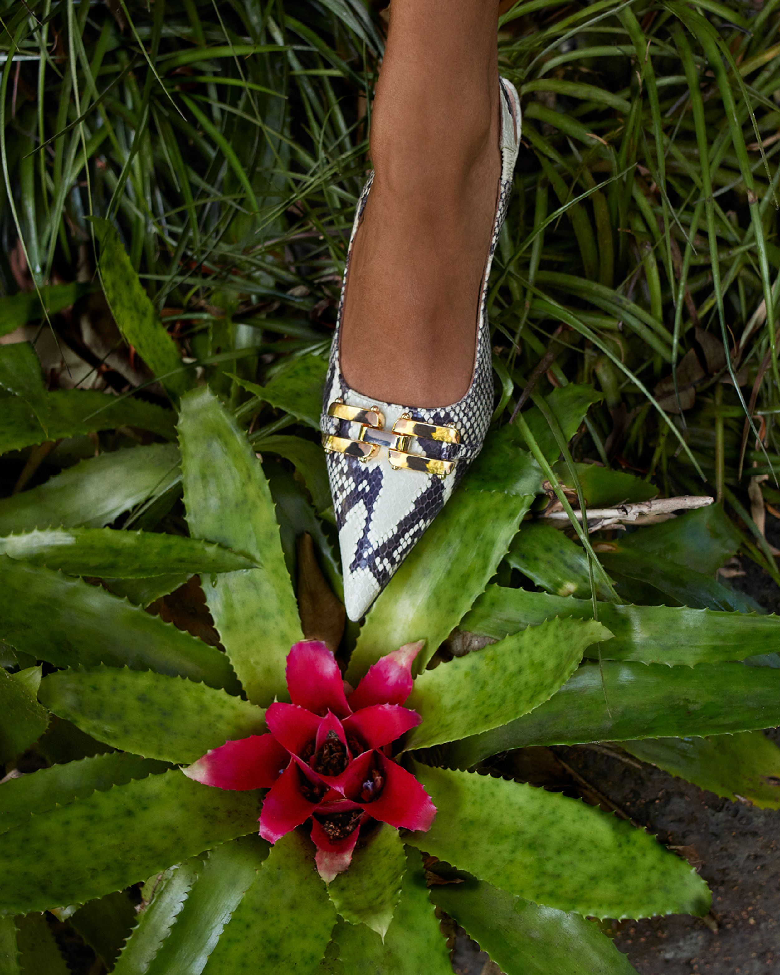 Detail shot of pointed white reptile-print pumps with gold chain detailing