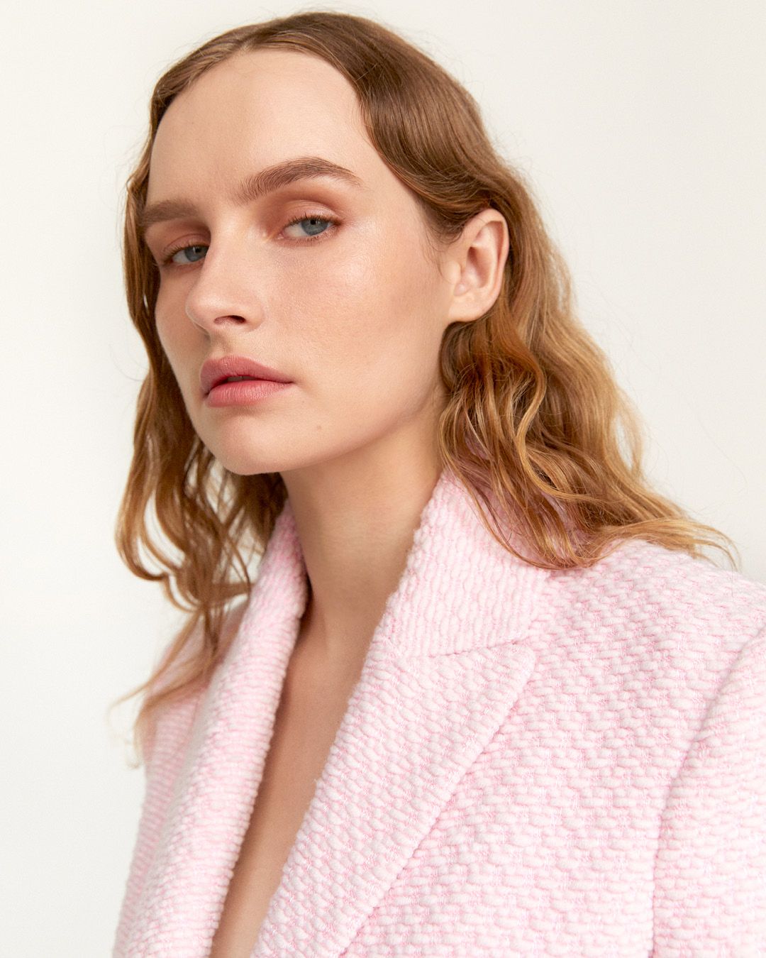 Olivia DeJonge with hair down wearing a light pink boucle jacket