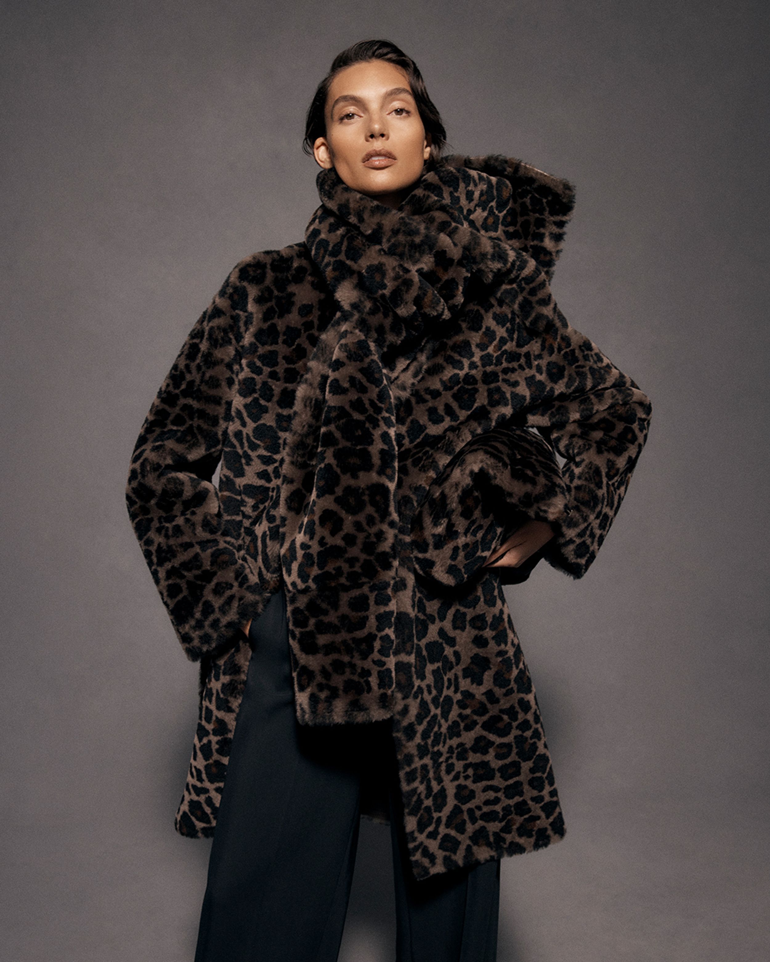 Brunette model wearing a matching leopard-print coat and scarf