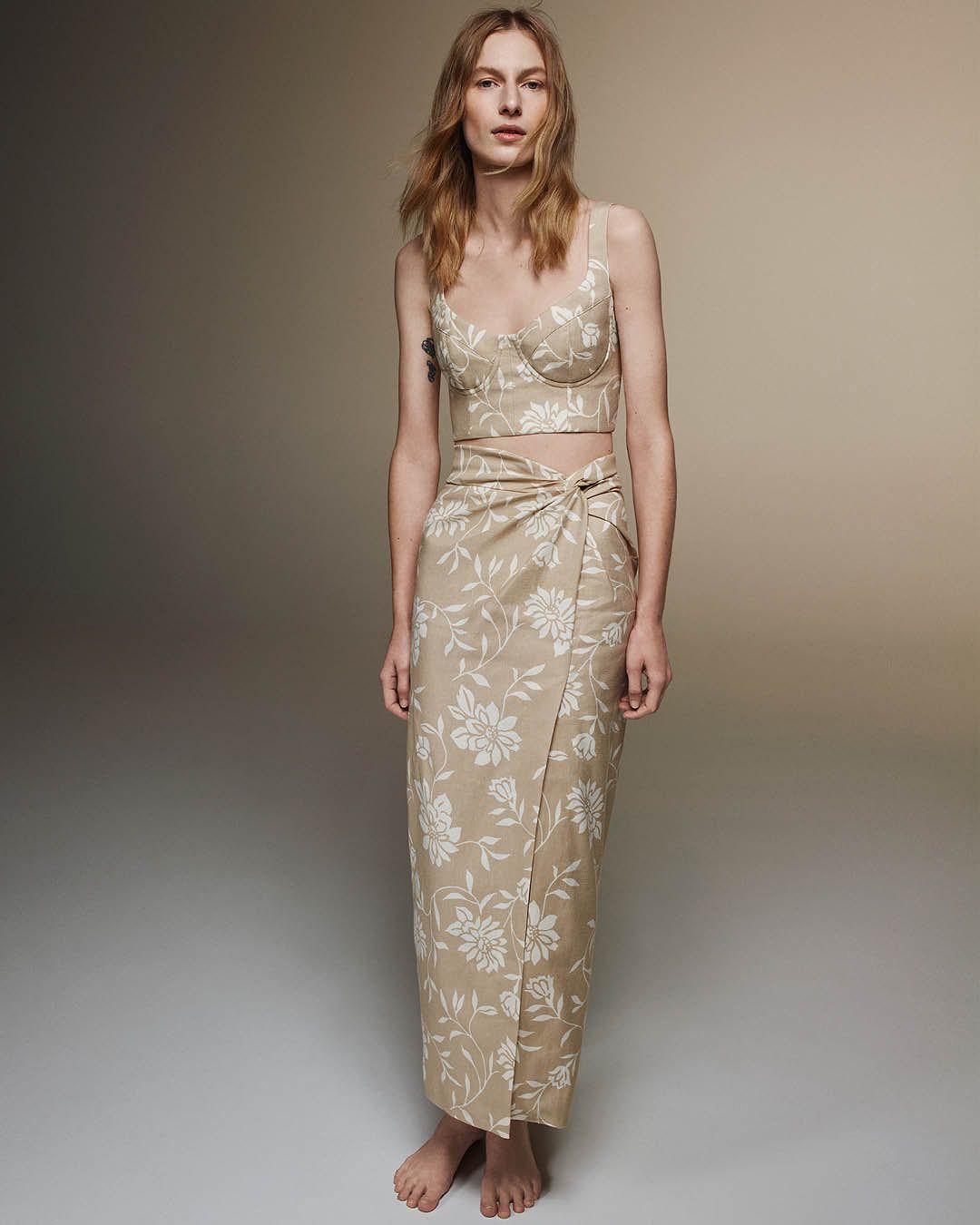 Julia Nobis standing in a matching linen bustier and skirt in beige with white floral print