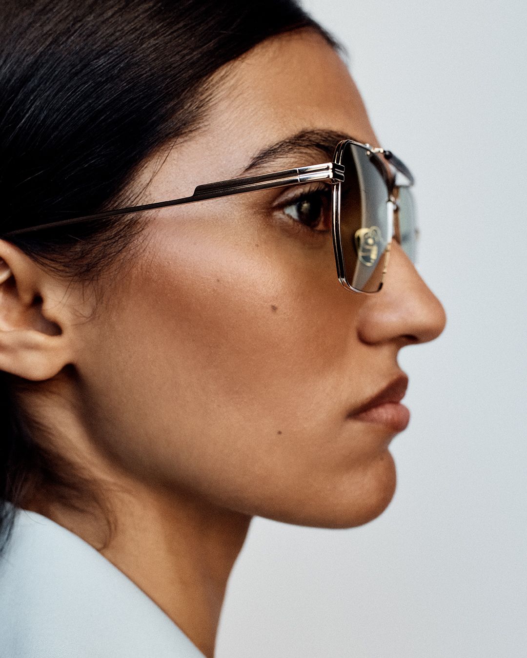 Close up of model's face looking to the side wearing aviator sunglasses
