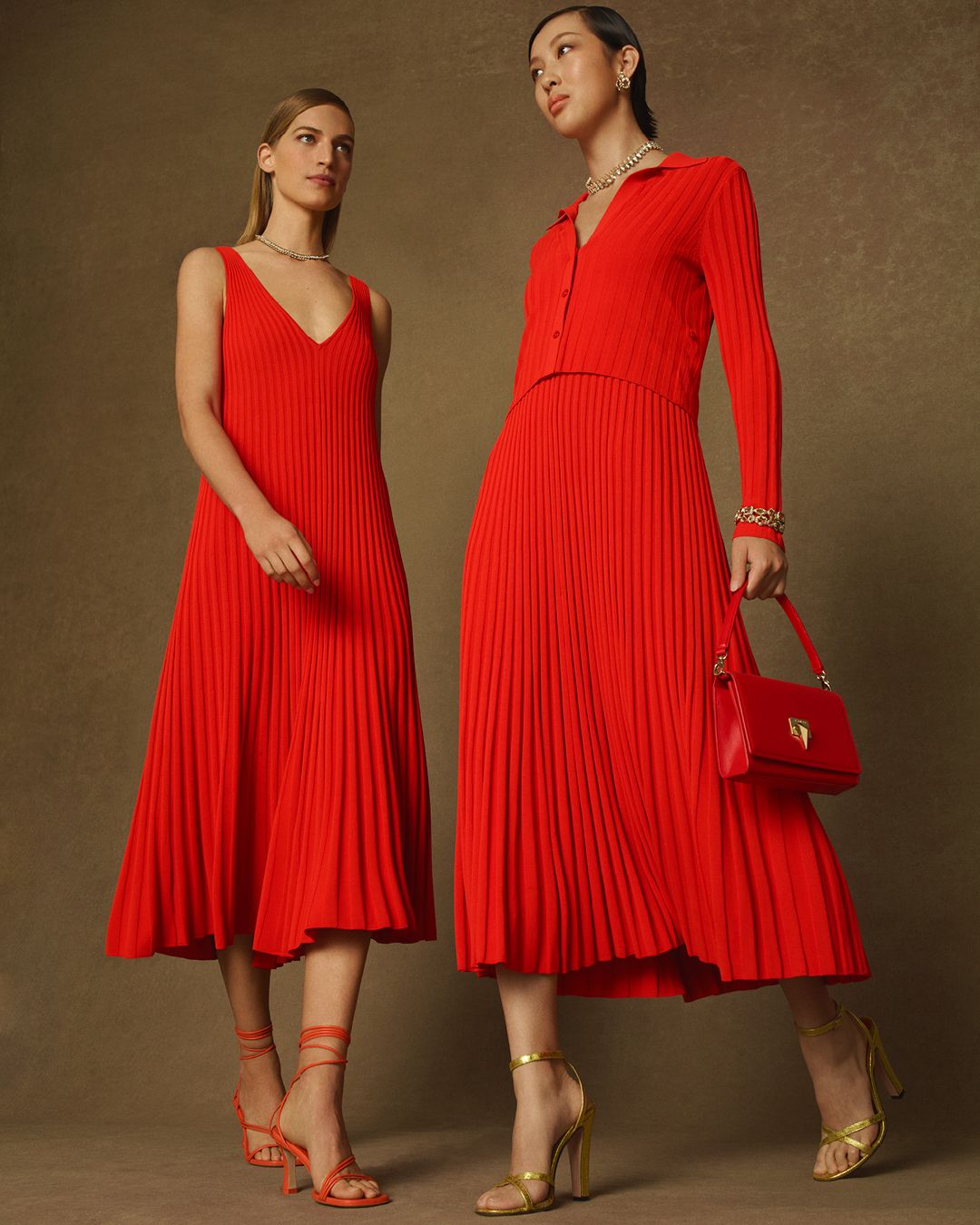 Two models walking towards each other wearing red pleated outfits