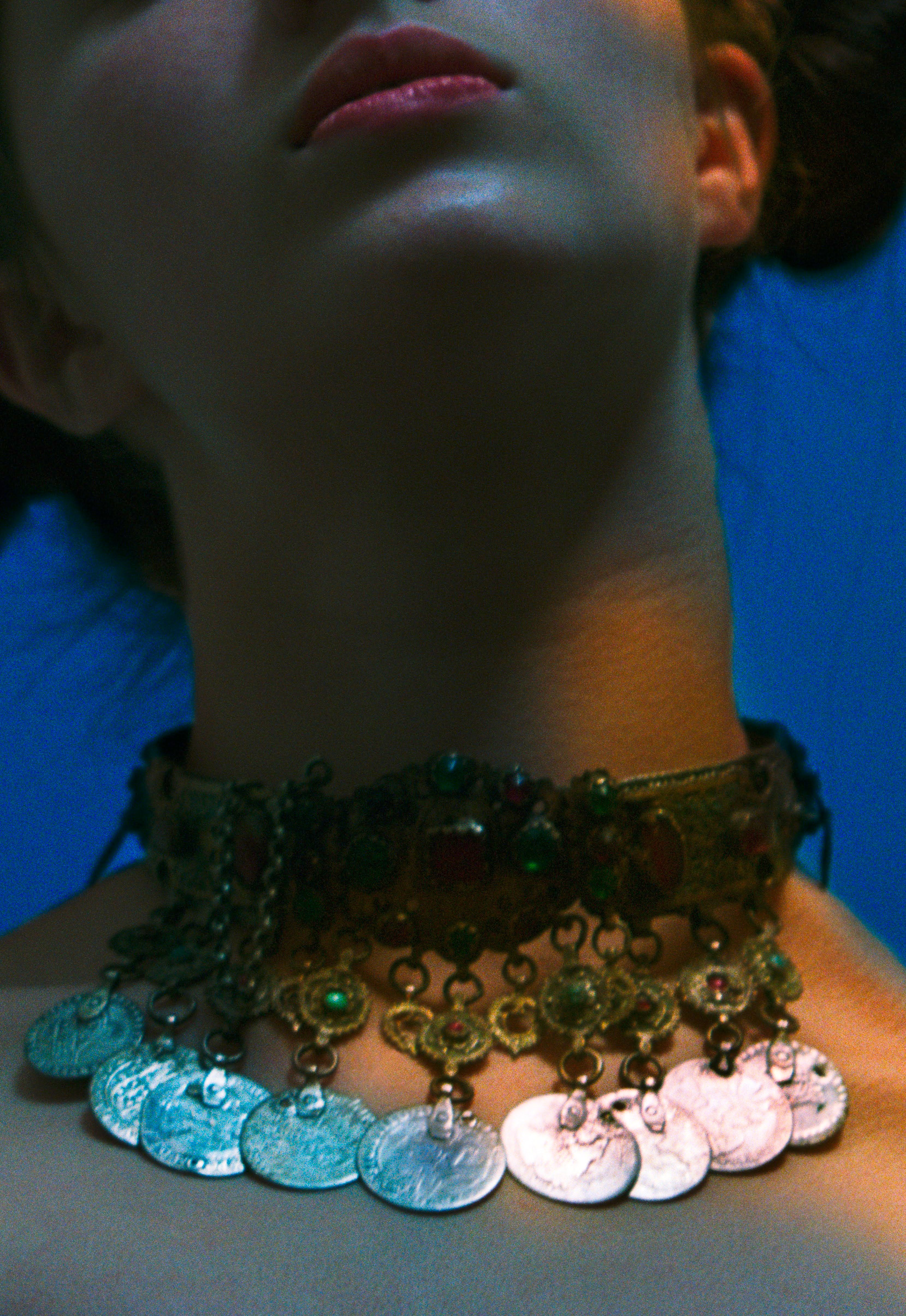 Close up of woman's neck wearing an Ancient Greek necklace with gemstones and coins