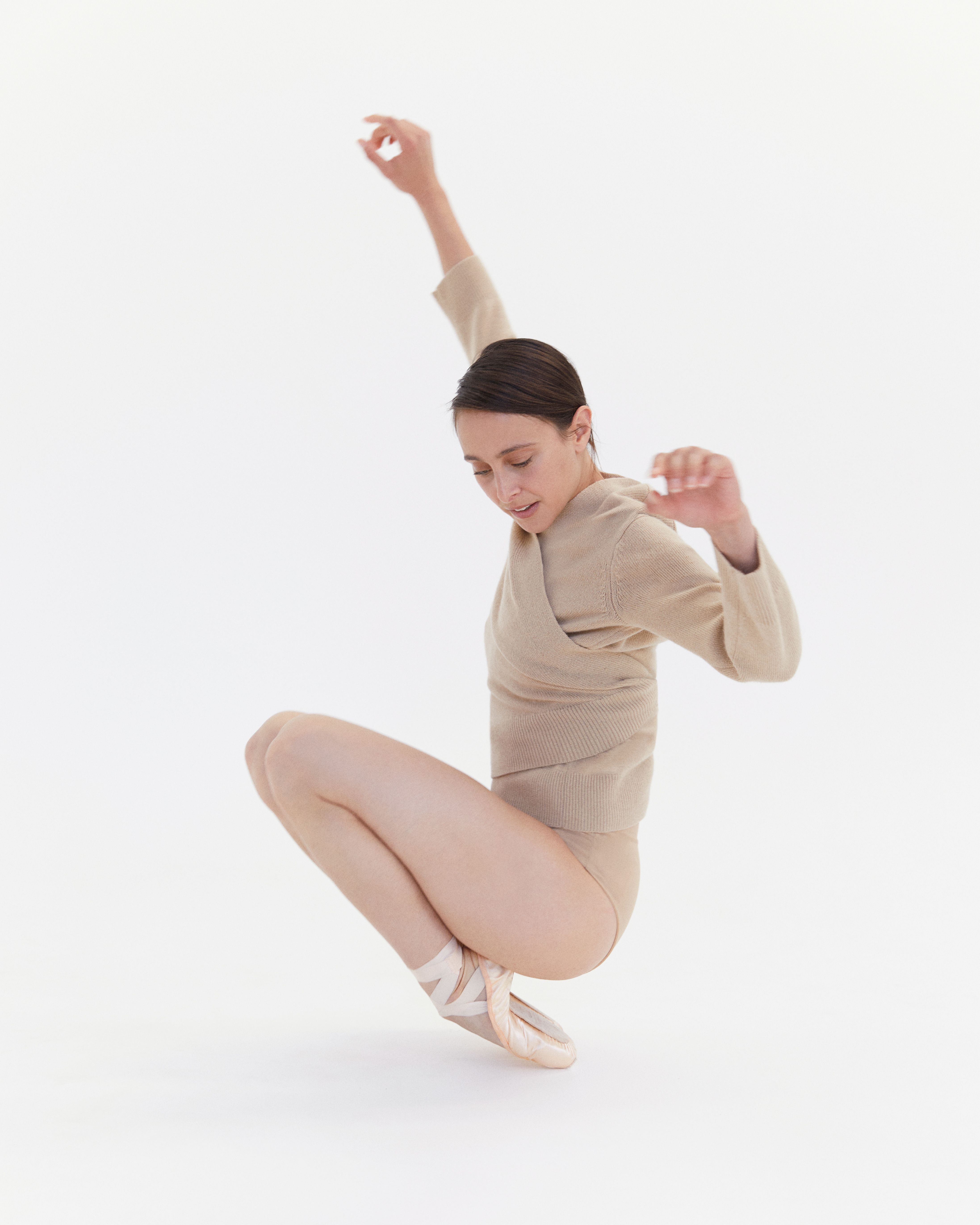 Dimity Azoury kneeling wearing a beige knit and pointe shoes