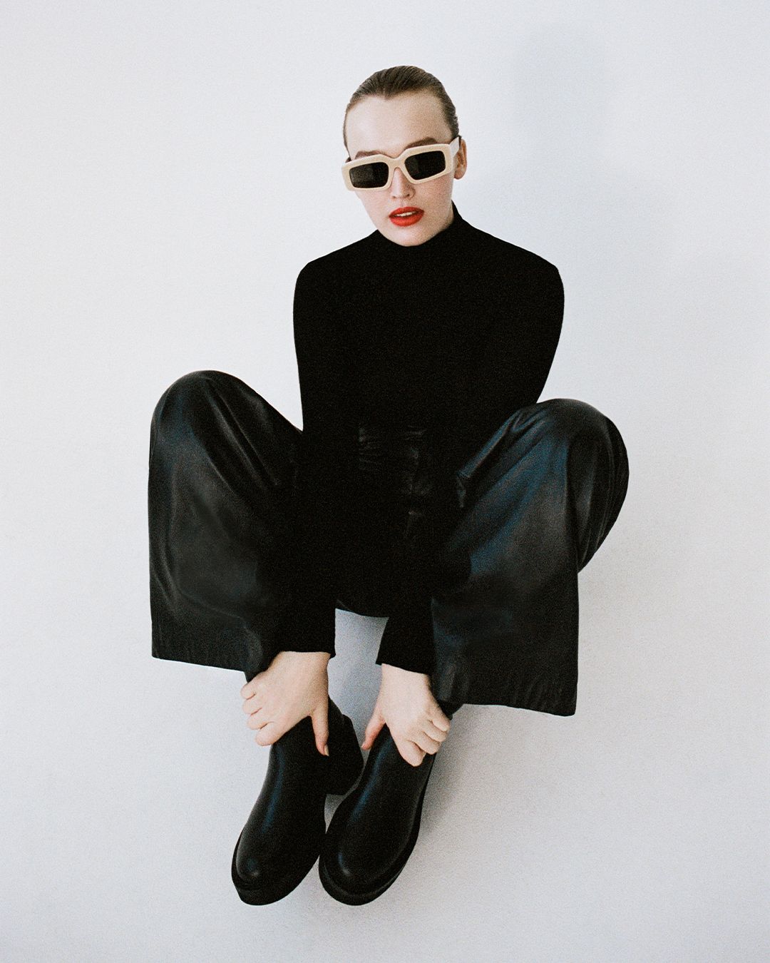 Maddison Brown sitting on the floor in black outfit with sunglasses