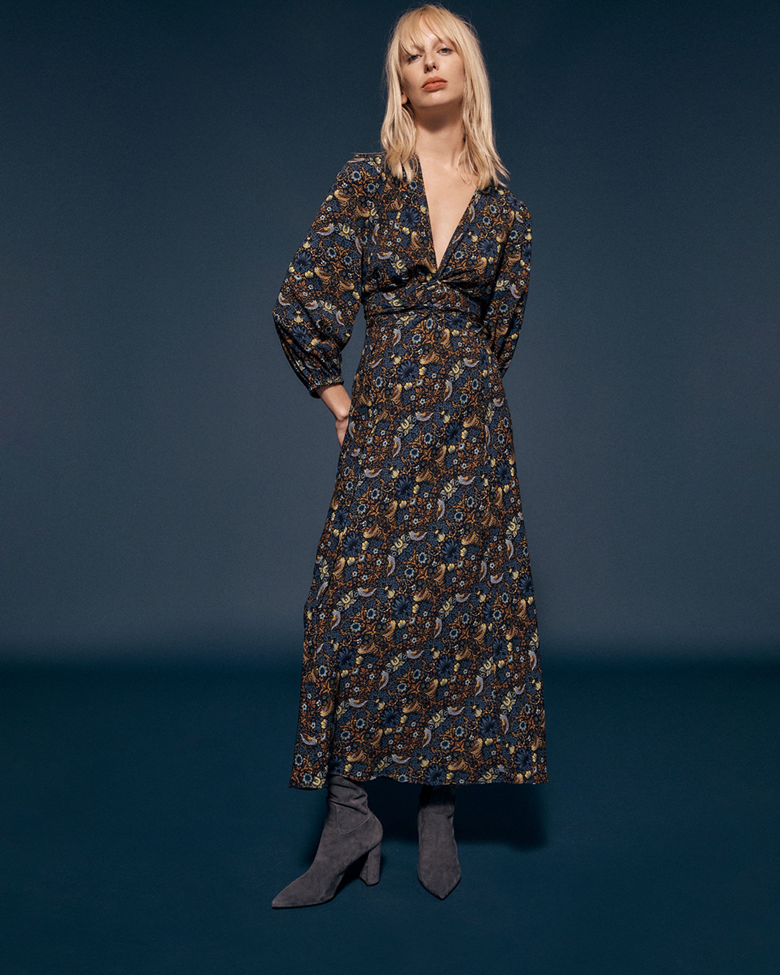 Blonde model standing in a navy floral-print dress