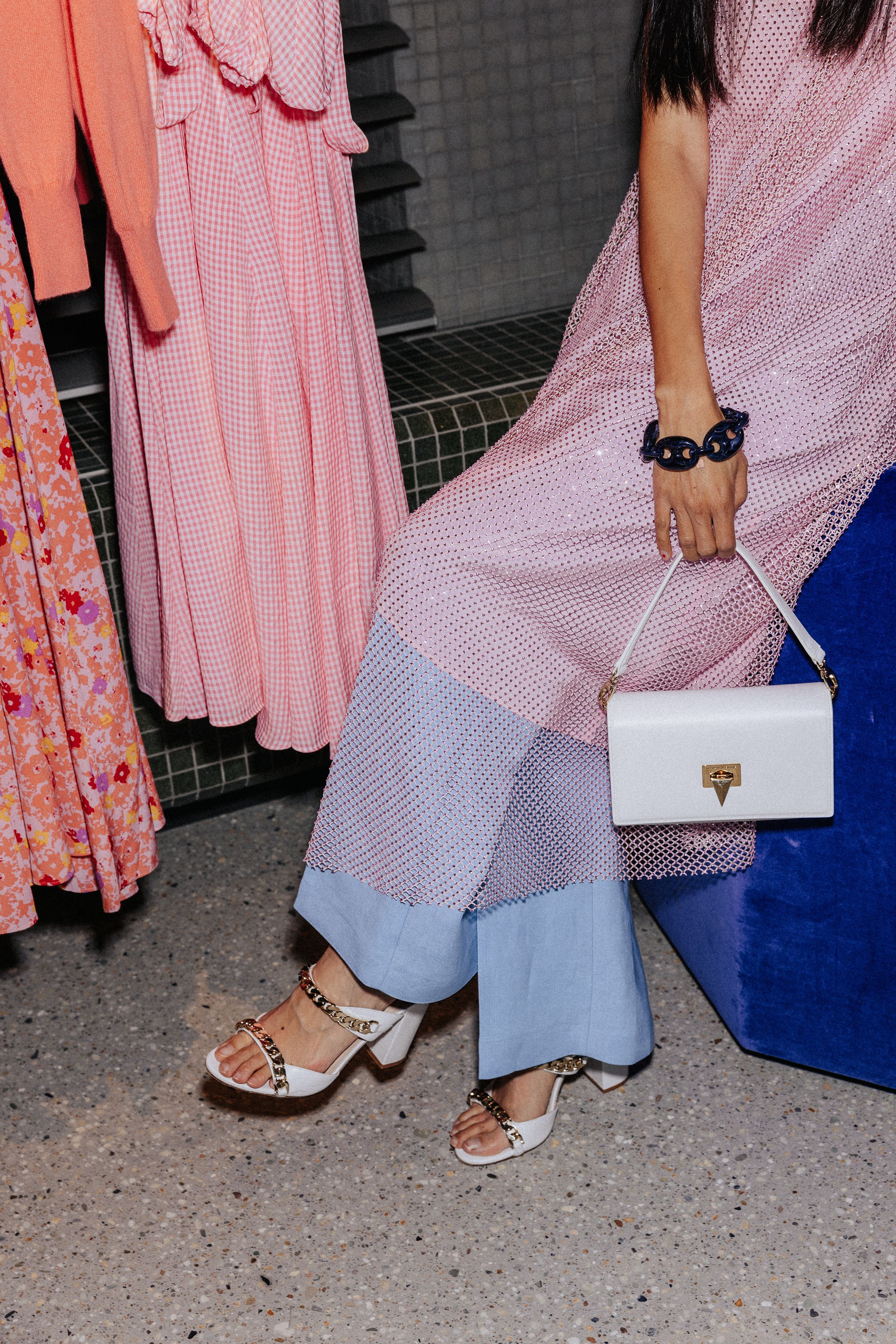 Woman sitting wearing pink dress and blue trousers 