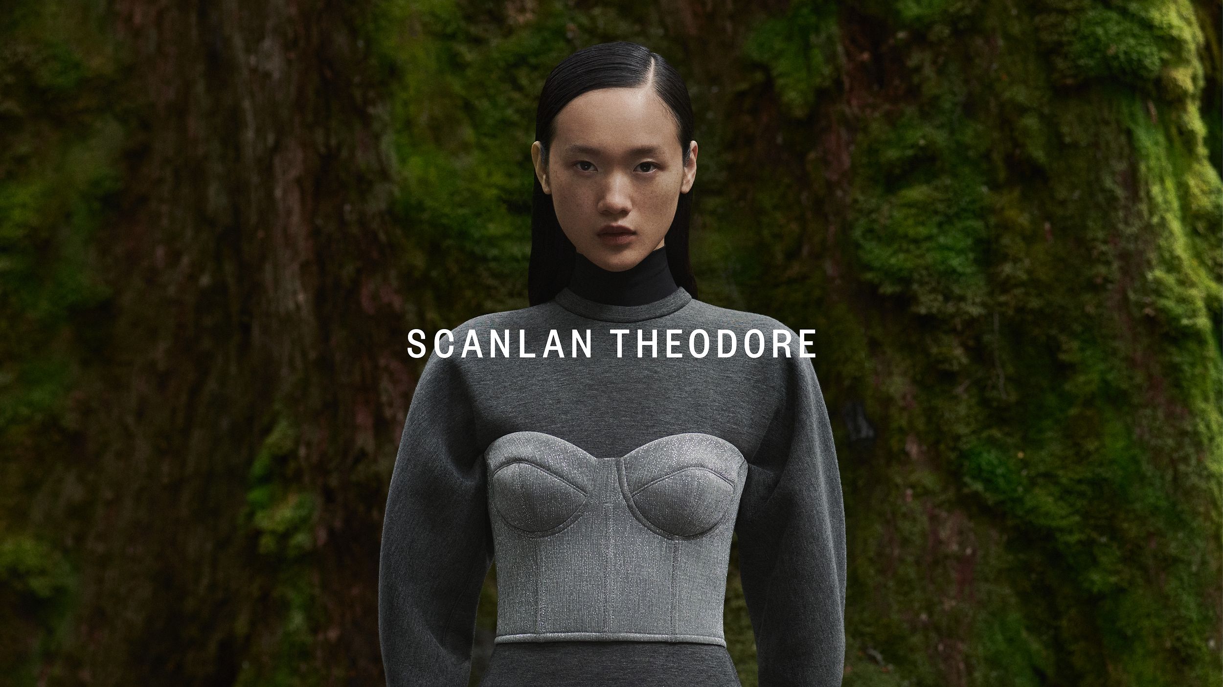 Venus He gazing at the camera wearing a charcoal long-sleeved dress with silver bustier on top