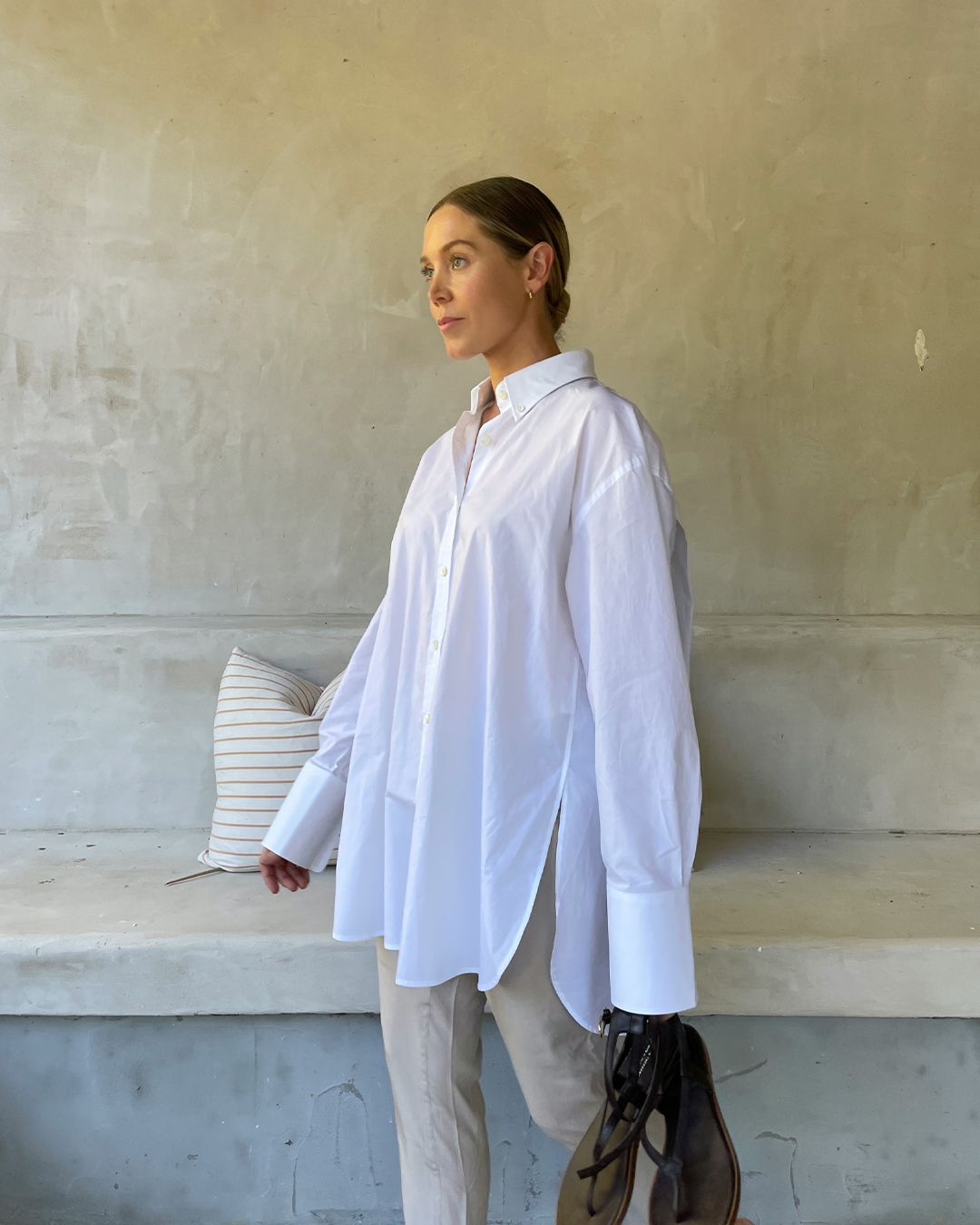 Hayley Bonham in white crisp shirting with a sleek bun hair style and tailored workwear trousers