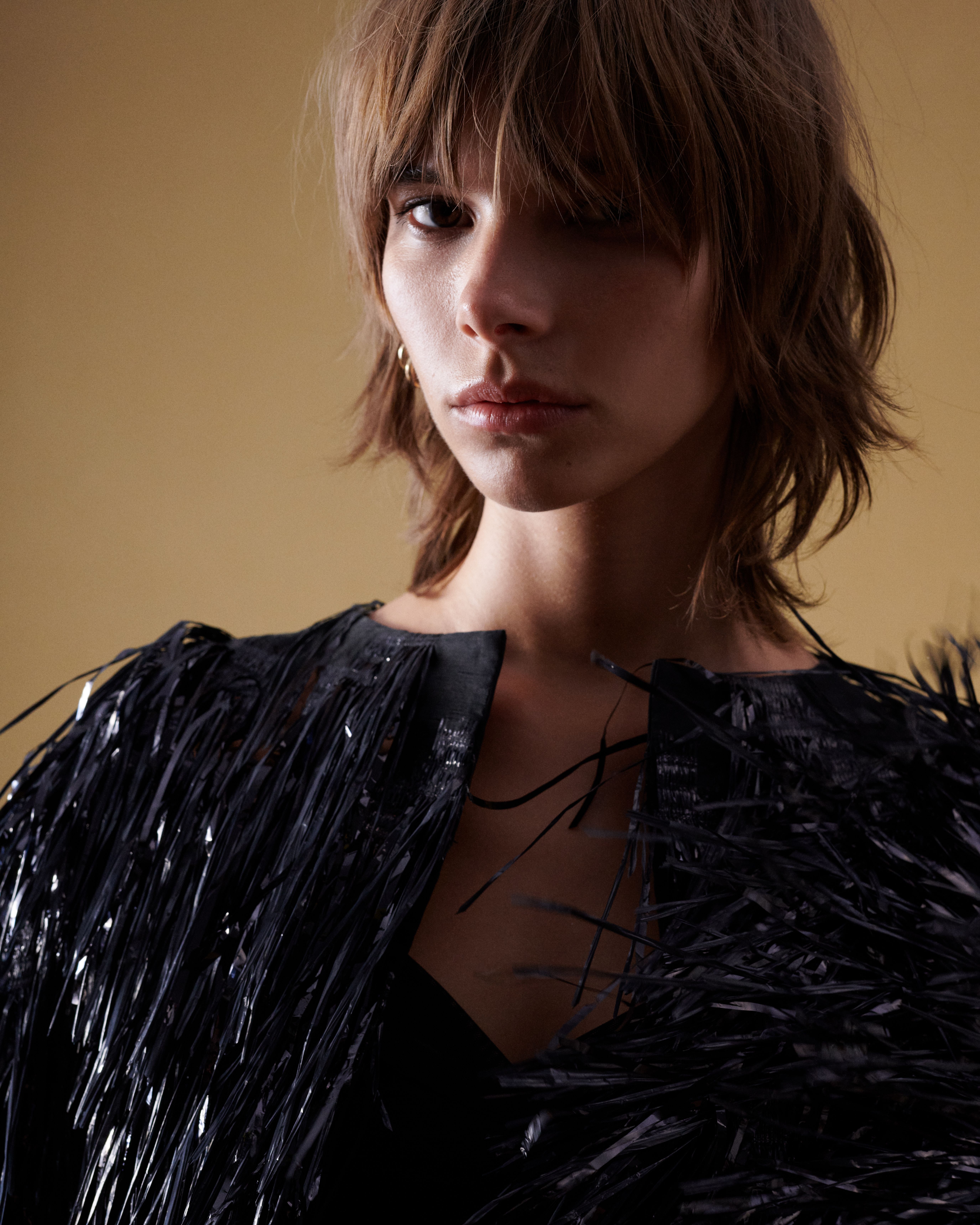 Close up of model wearing a black fringed jacket