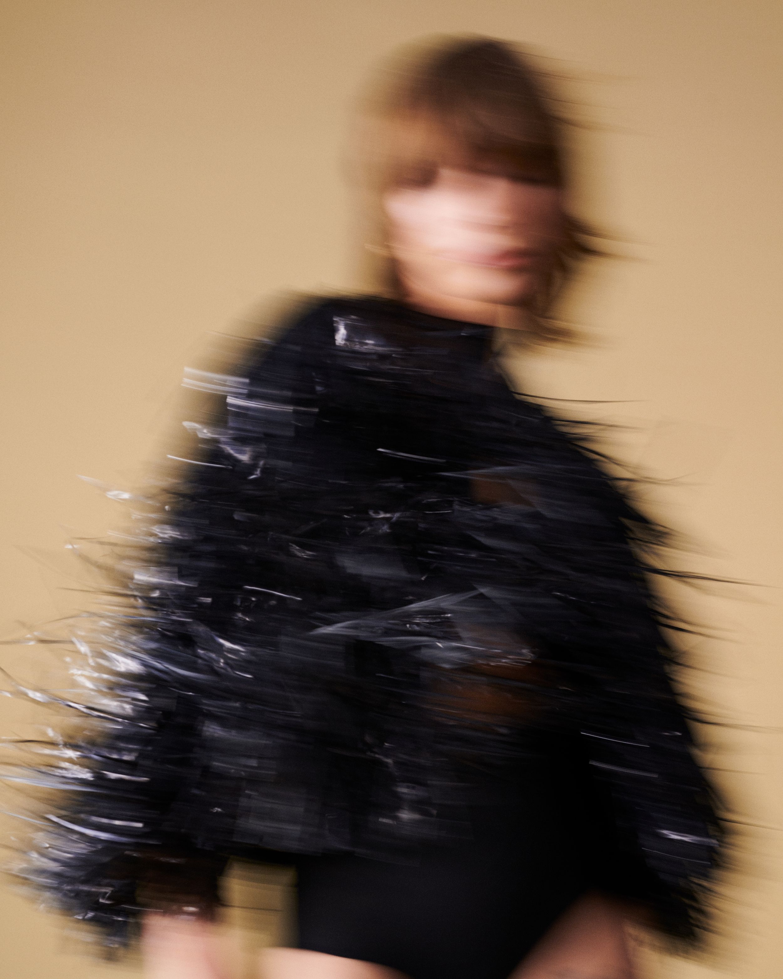Blurred image of woman moving in a black tinsel fringed jacket