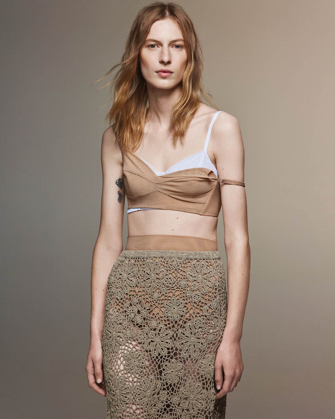 Julia Nobis wearing a beige mesh bra layered over a white mesh bra and taupe crocheted skirt