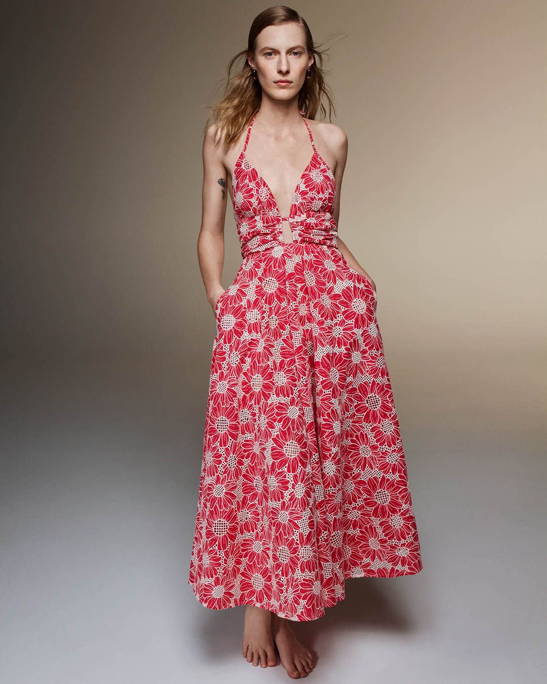 Julia Nobis standing with hands in pockets wearing a pink floral embroidered long dress